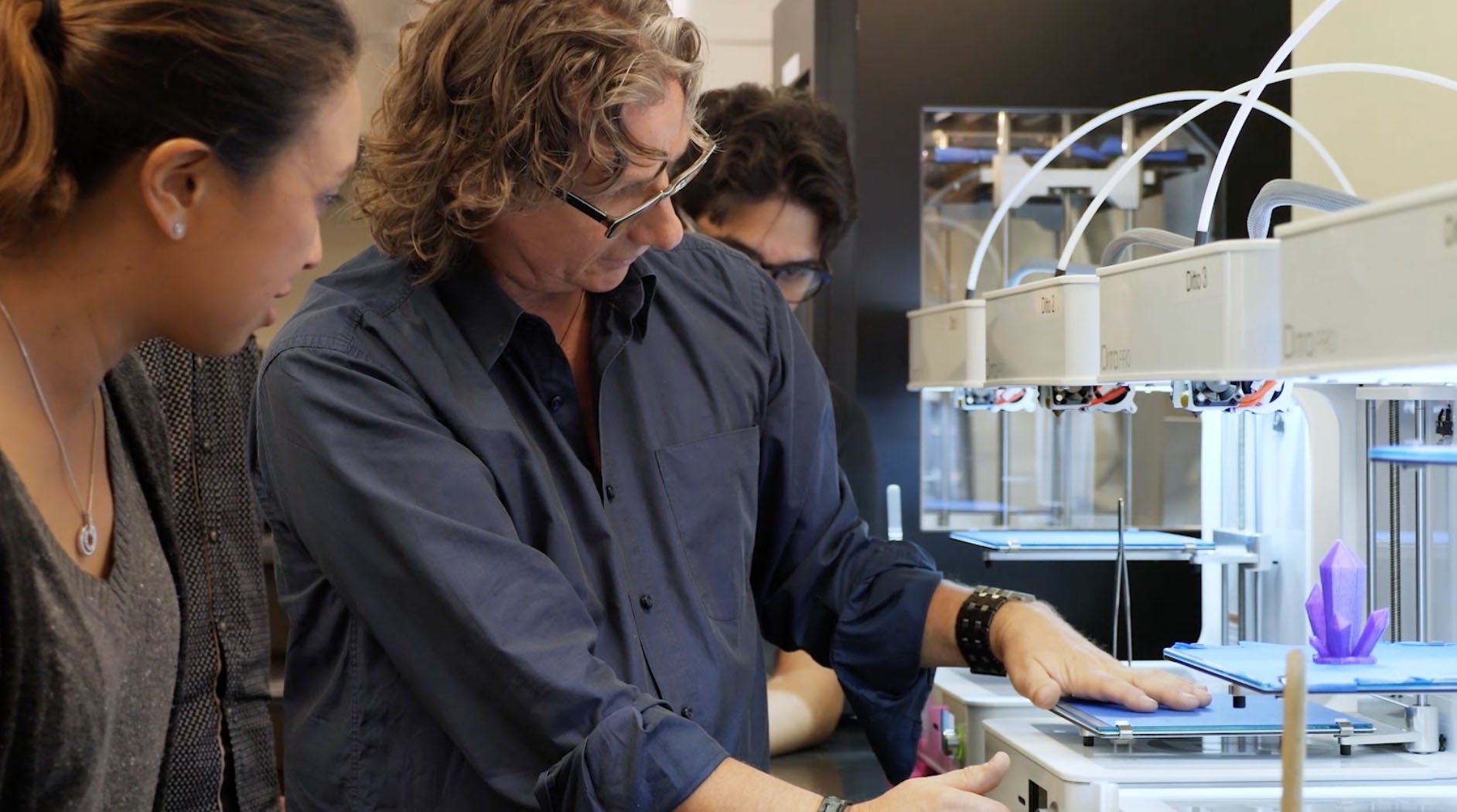 An instructor showing students how to use 3D printers.