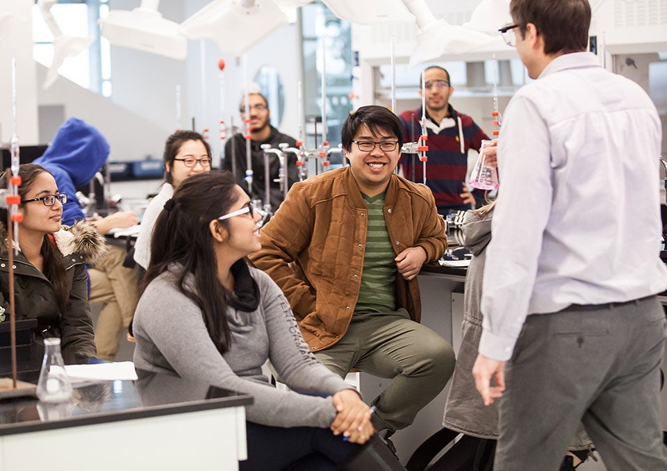 A dynamic faculty member leads an engaging laboratory session, where students are eagerly participating and sharing smiles as they explore new concepts together.
