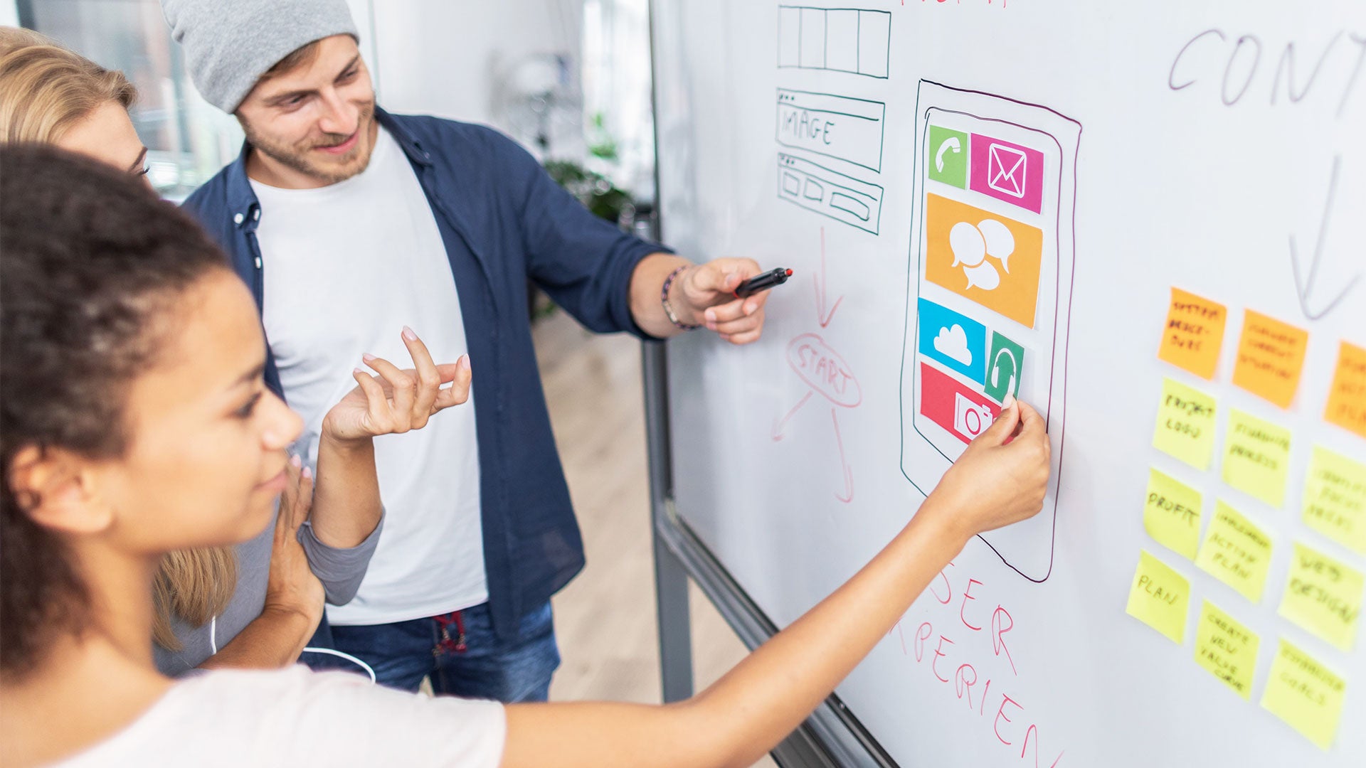 A group of students learn and discuss about wireframes on a whiteboard.