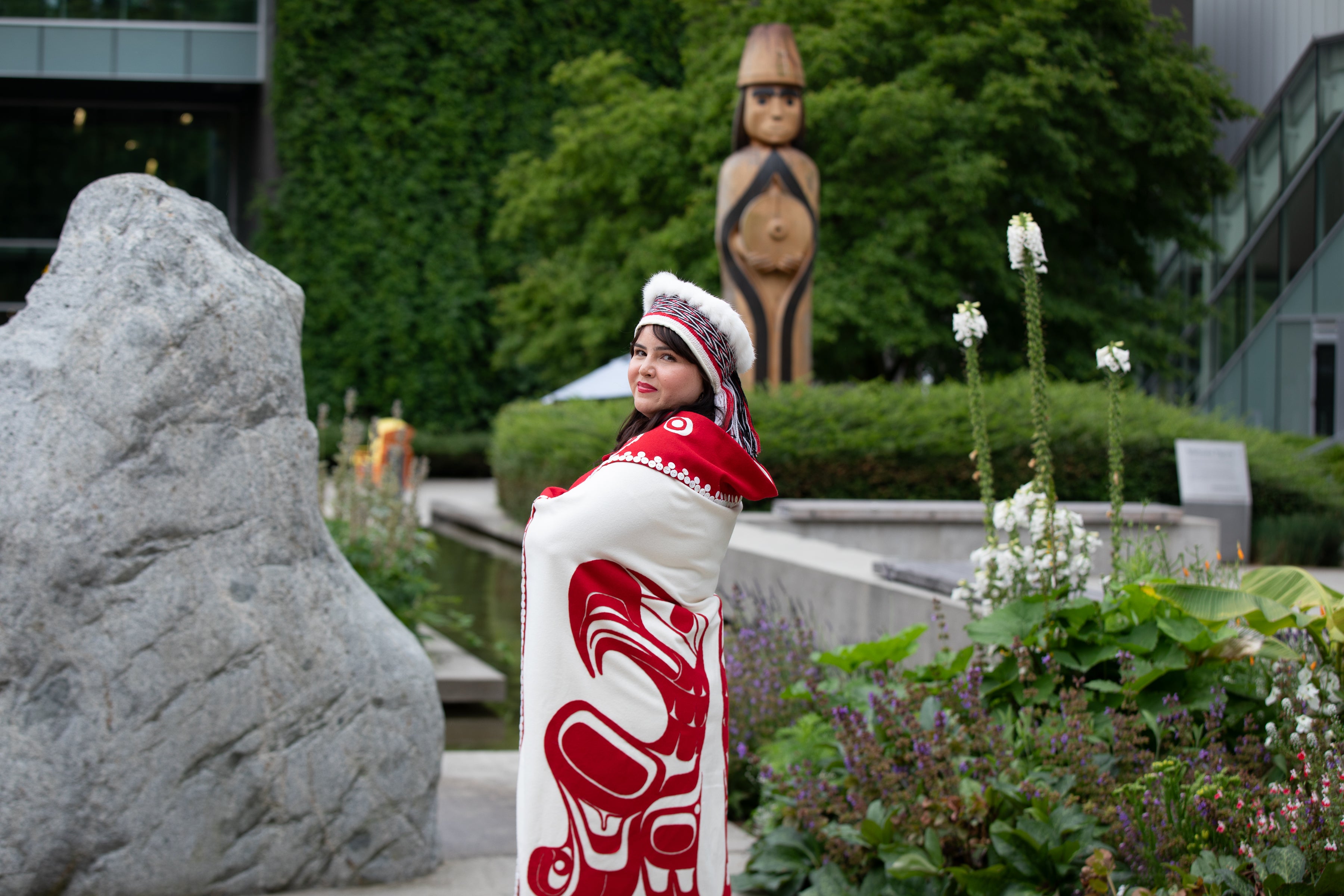 Bachelor of Science in Nursing graduate, Cecelia Simeon, wearing traditional Haida garments, posing in front of Langara College's Musqueam house post.