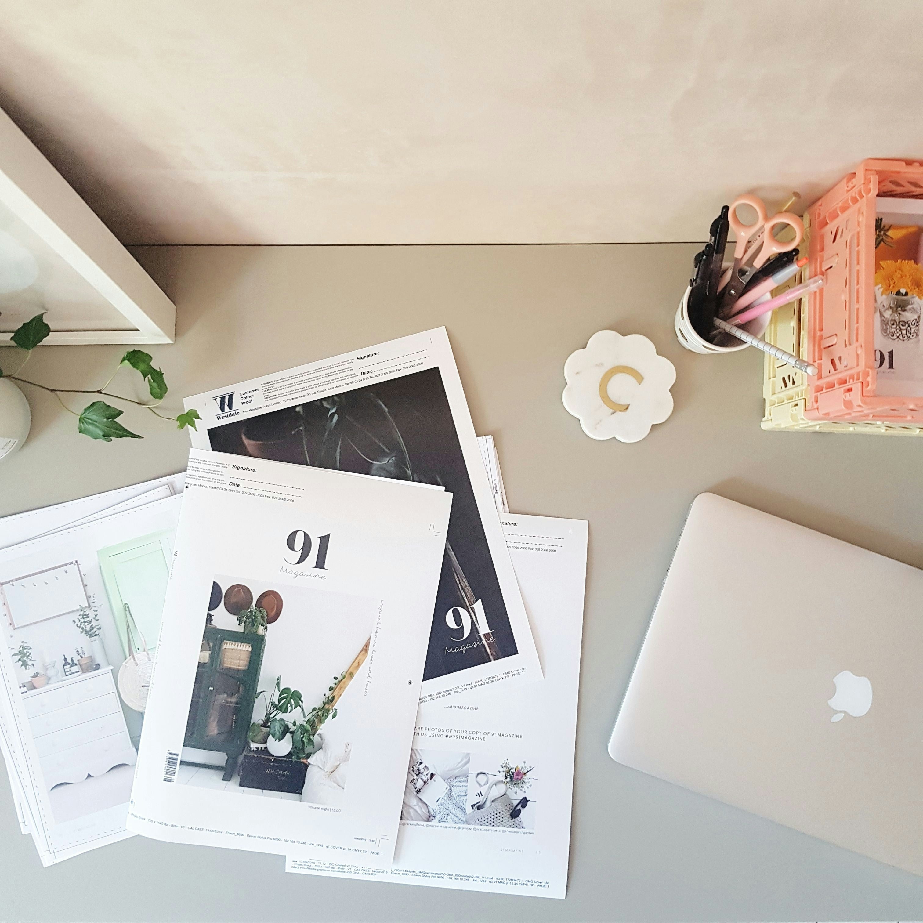 Magazine pages on a desk, a macbook laptop is also nearby.