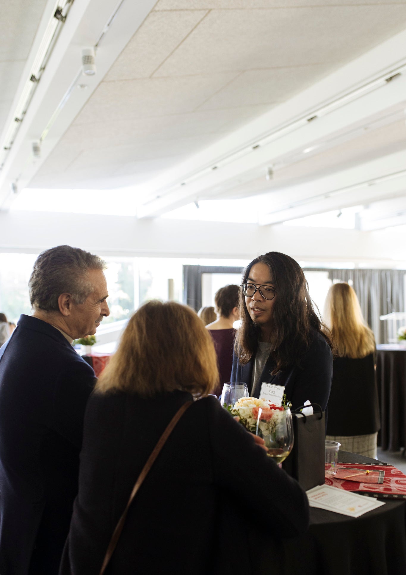 A student and two Langara donors standing and chatting at a table.