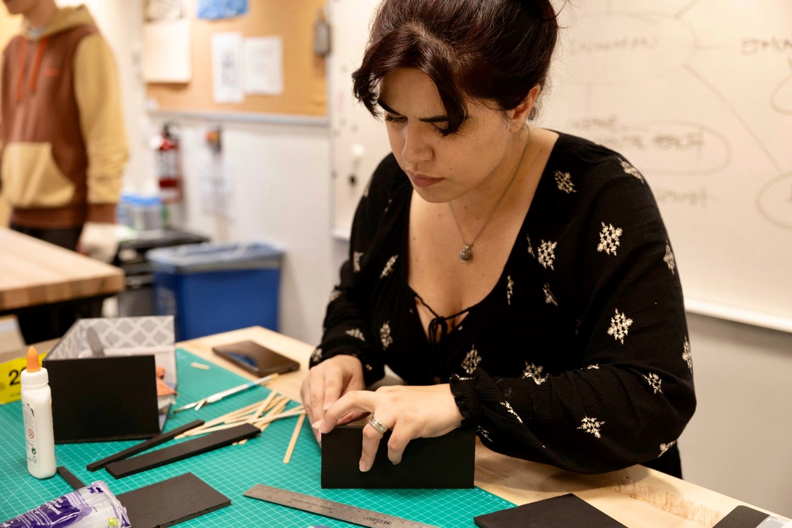 A student looking intently at a model they are making.
