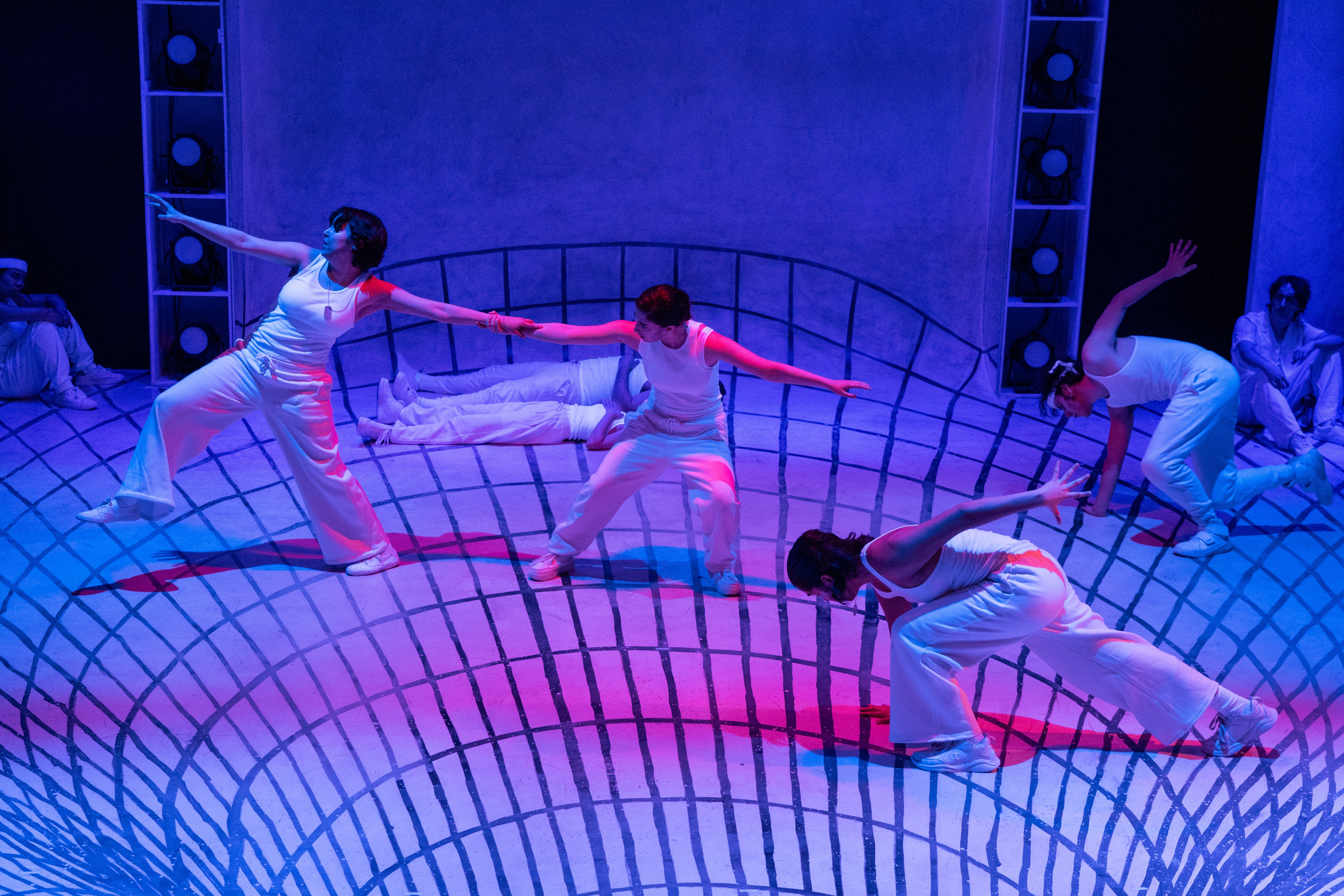 Actors dressed in white are dancing on stage, which is painted to look like they are falling into a vortex. 