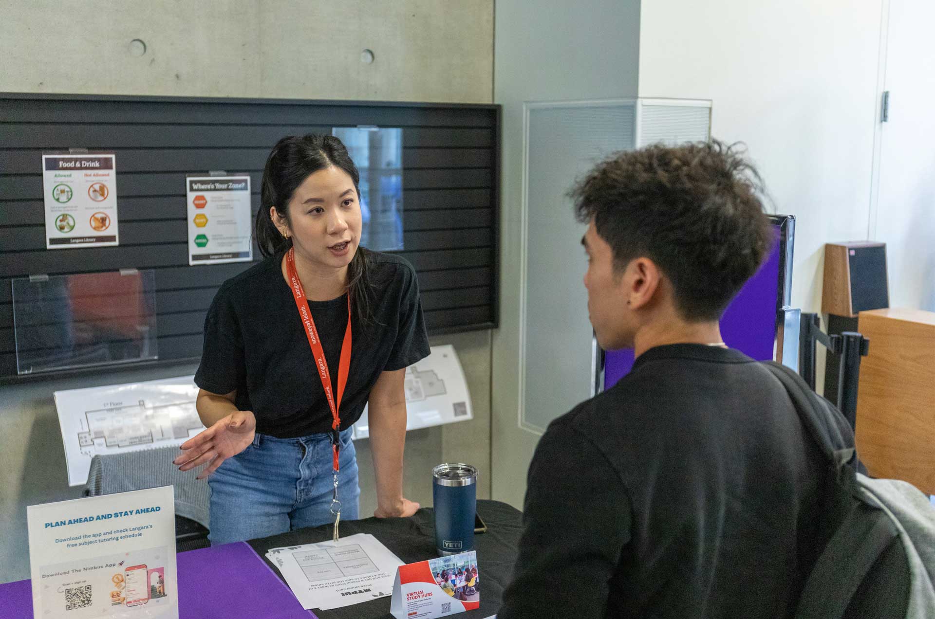 Academic Advisor speaks to a student at a university fair.