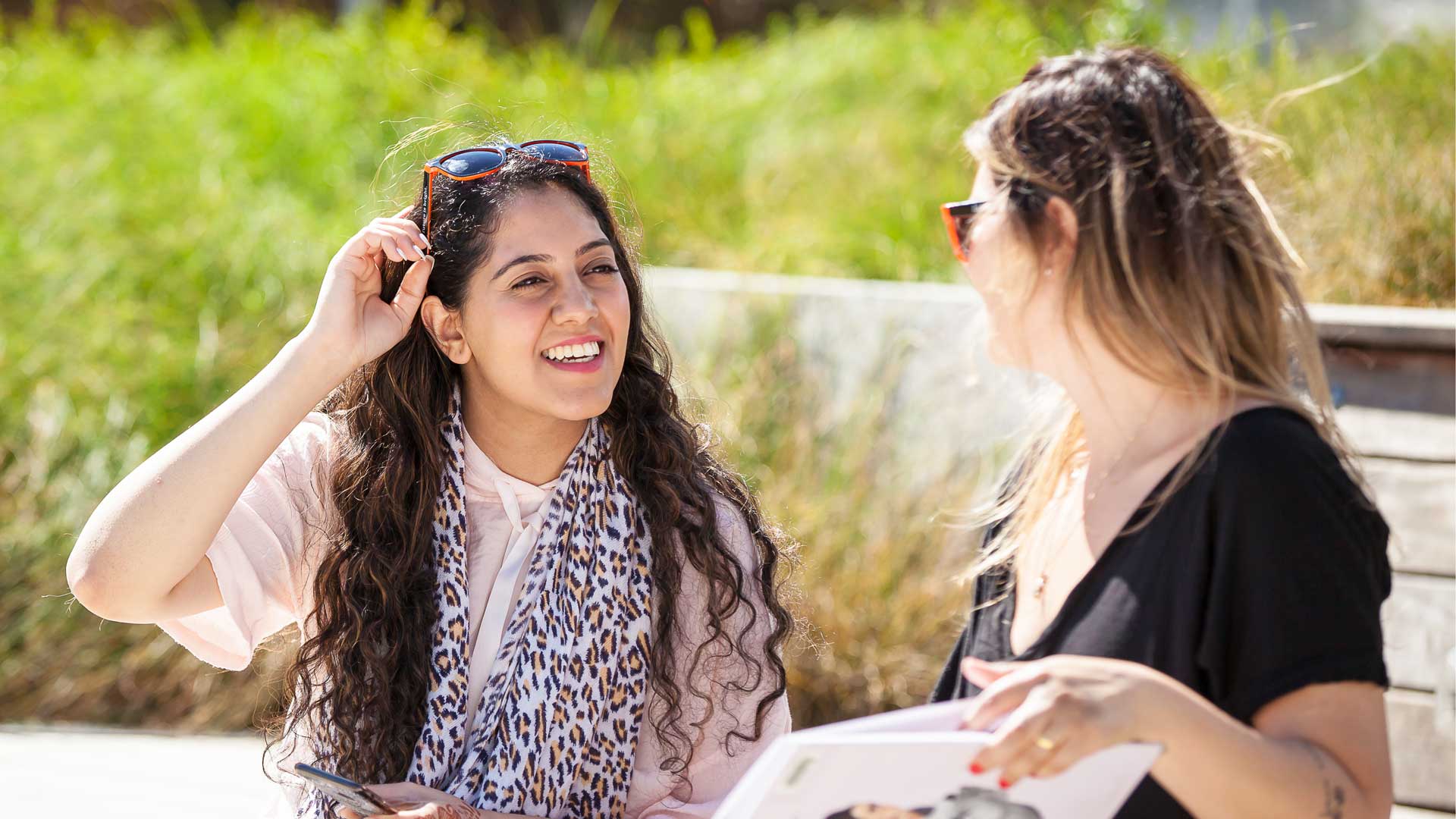 Two female-presenting students talk on Langara's main campus.