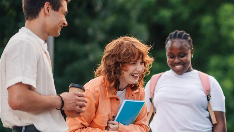 Three college students smiling while outdoors.