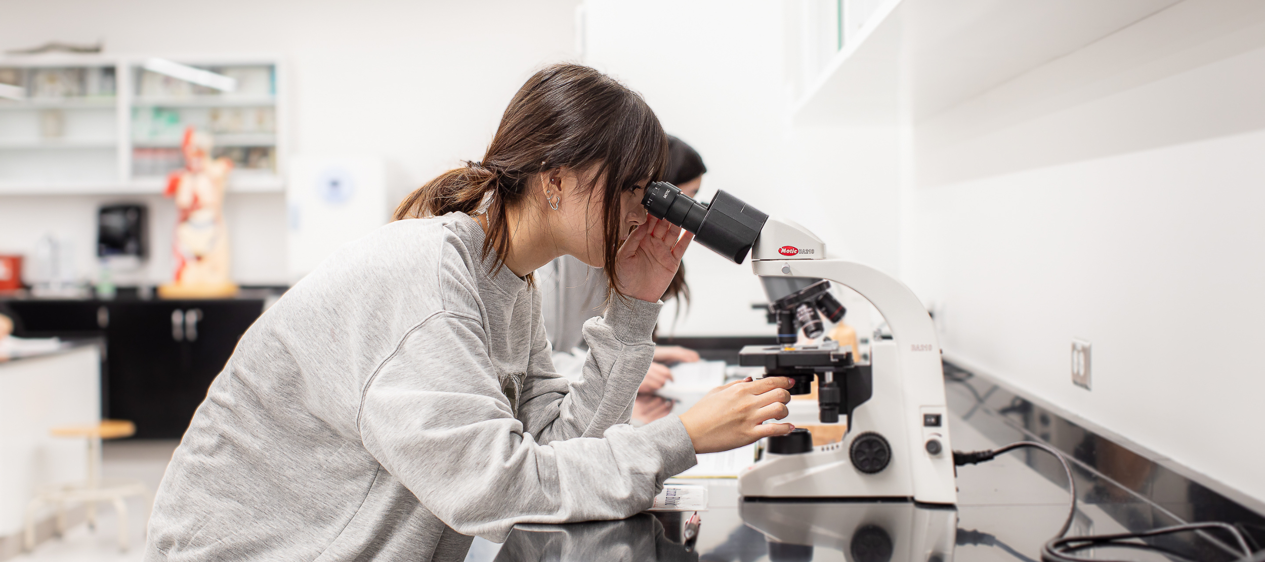 Asian Biology student looking into a microscope in the biology laboratory.