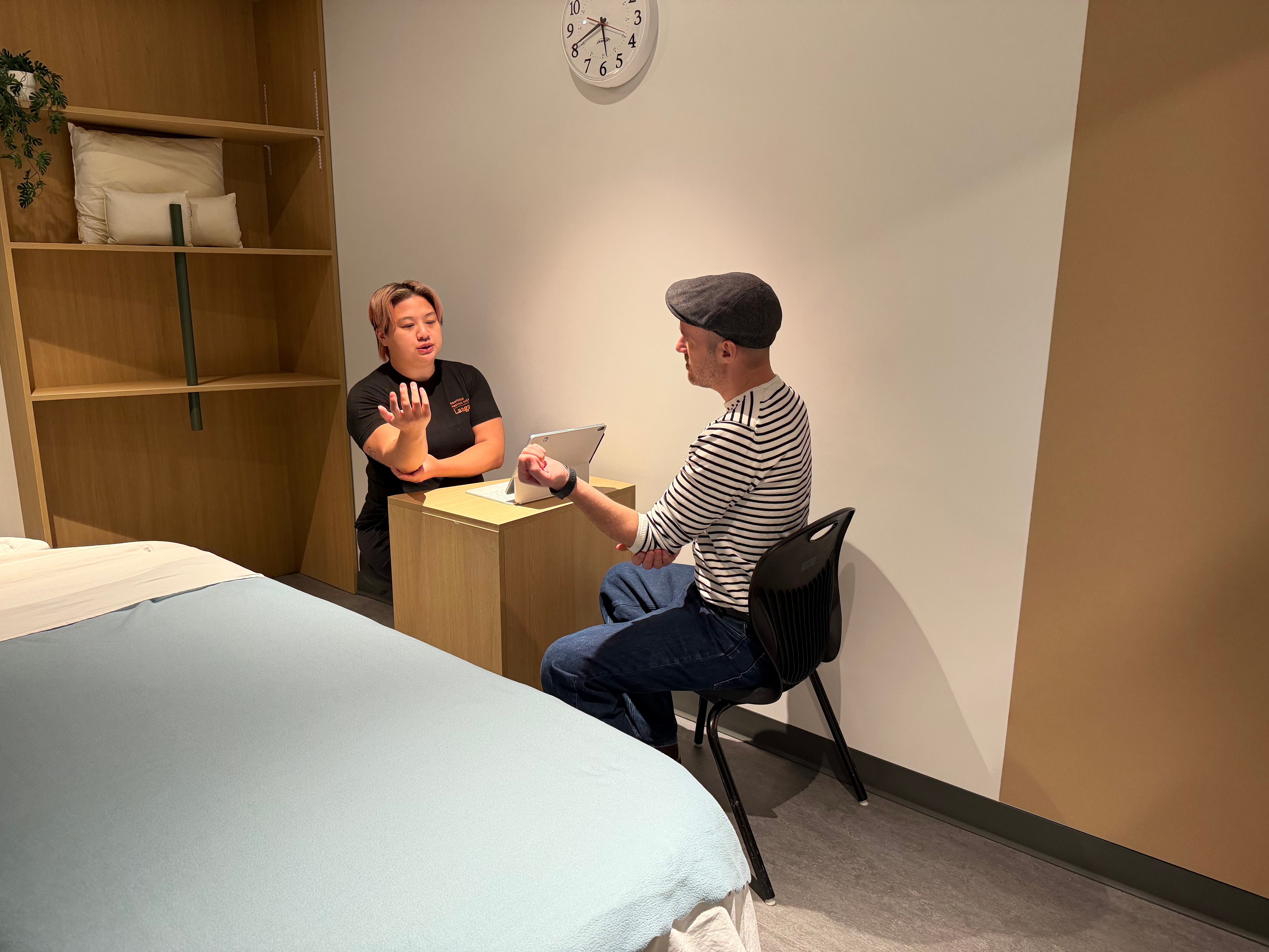 Second-year RMT student, Beverly Cheung, speaking with a client about his massage therapy needs.