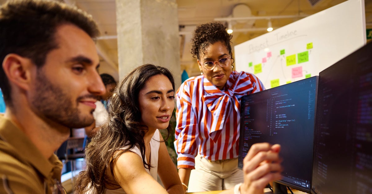 Three college students collaborating at a computer work station.