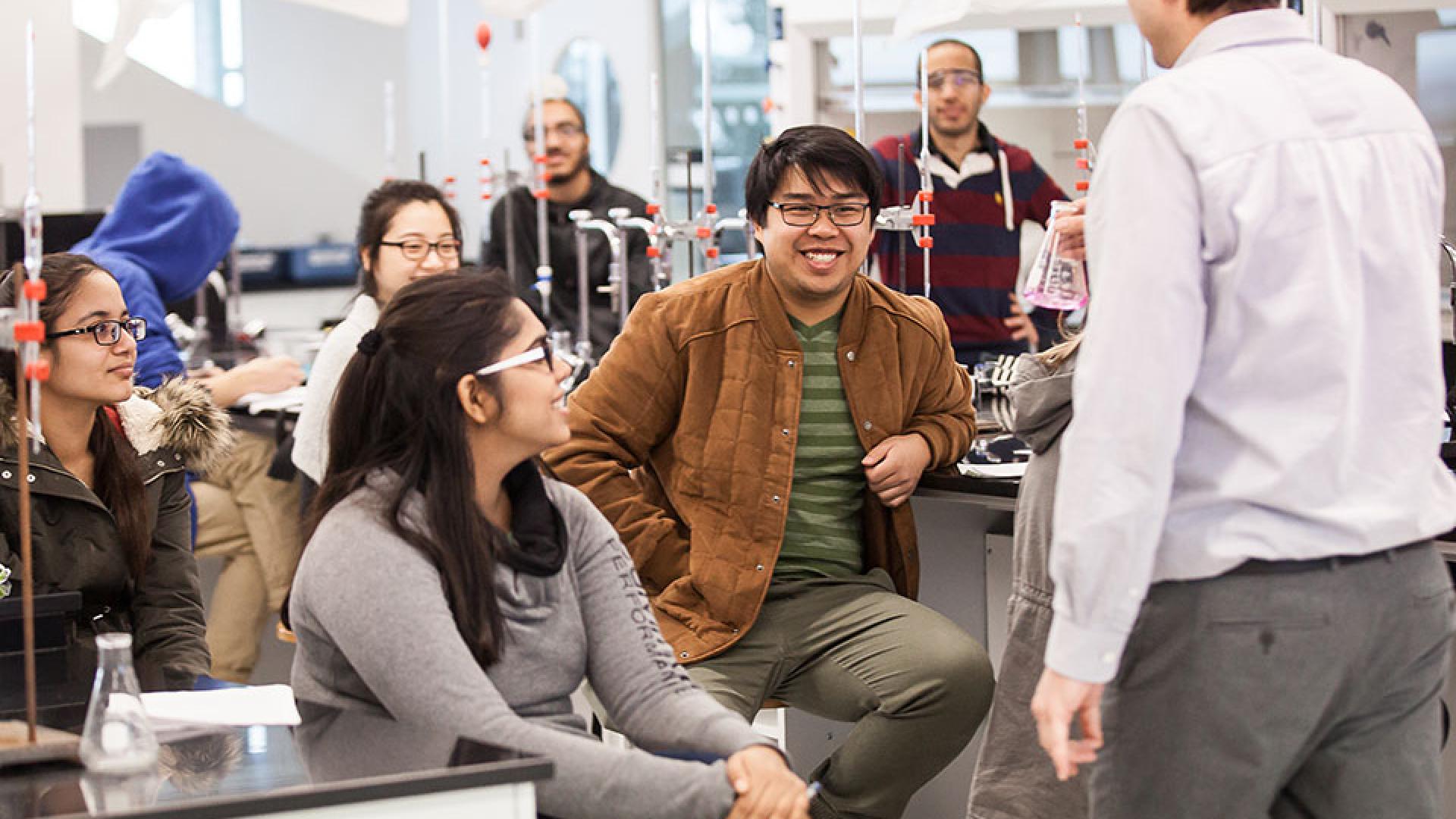 A dynamic faculty member leads an engaging laboratory session, where students are eagerly participating and sharing smiles as they explore new concepts together.