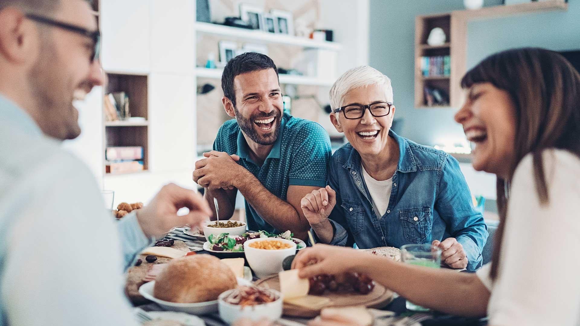 A family is sharing a table and having fun with their hosted international student.
