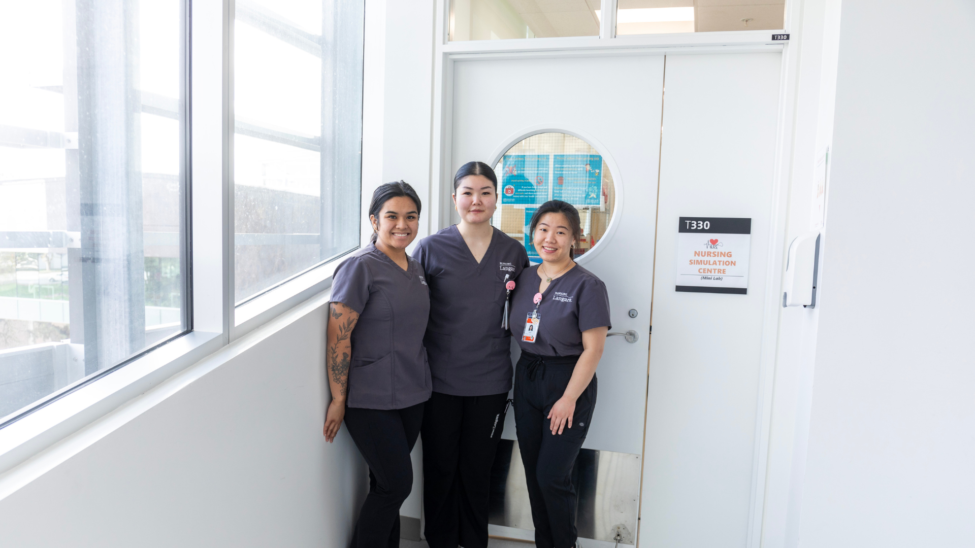Three students in front of the Langara Nursing Lab