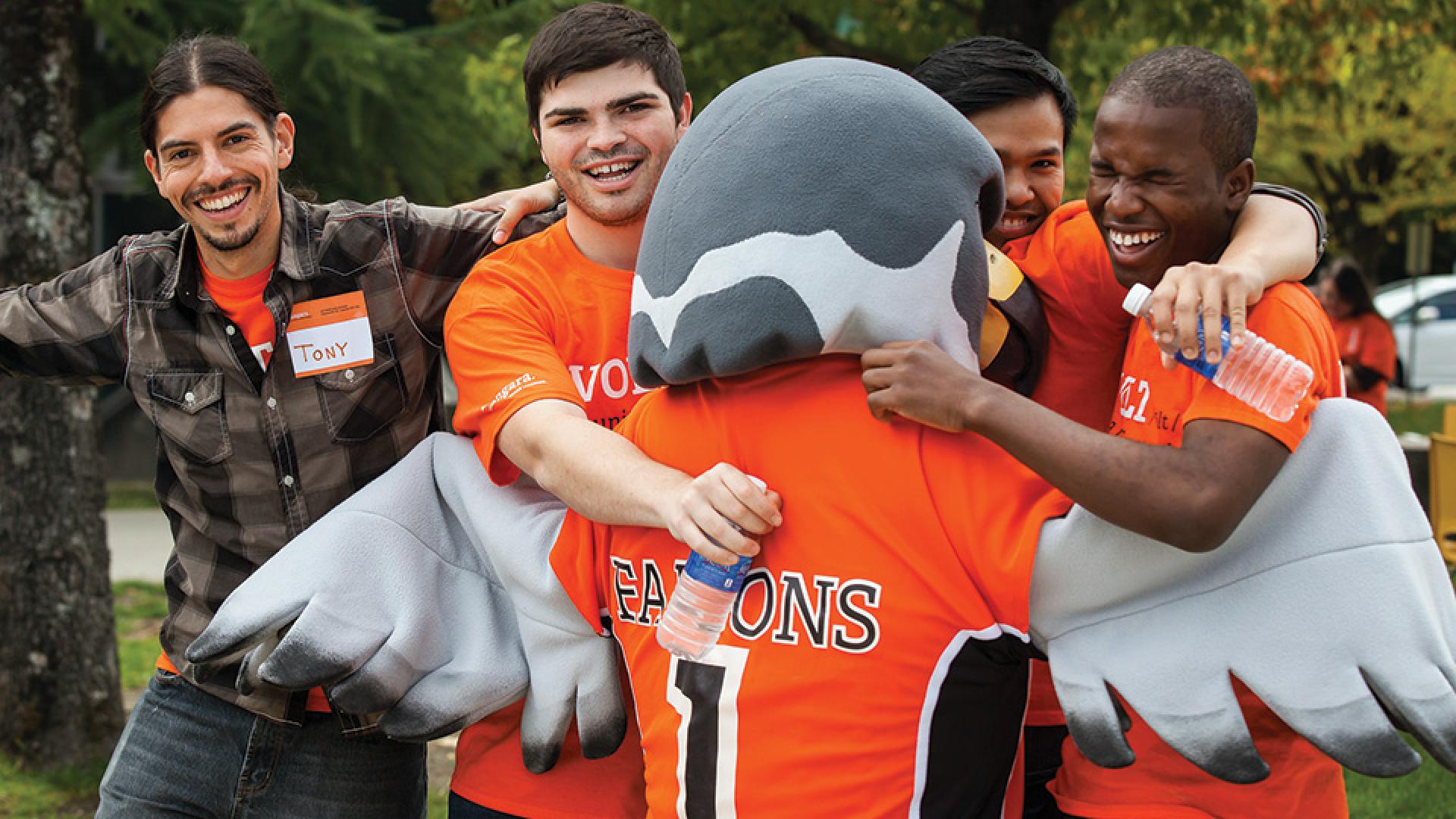 Students joyfully embracing the vibrant Langara Mascot, sharing smiles and a sense of community