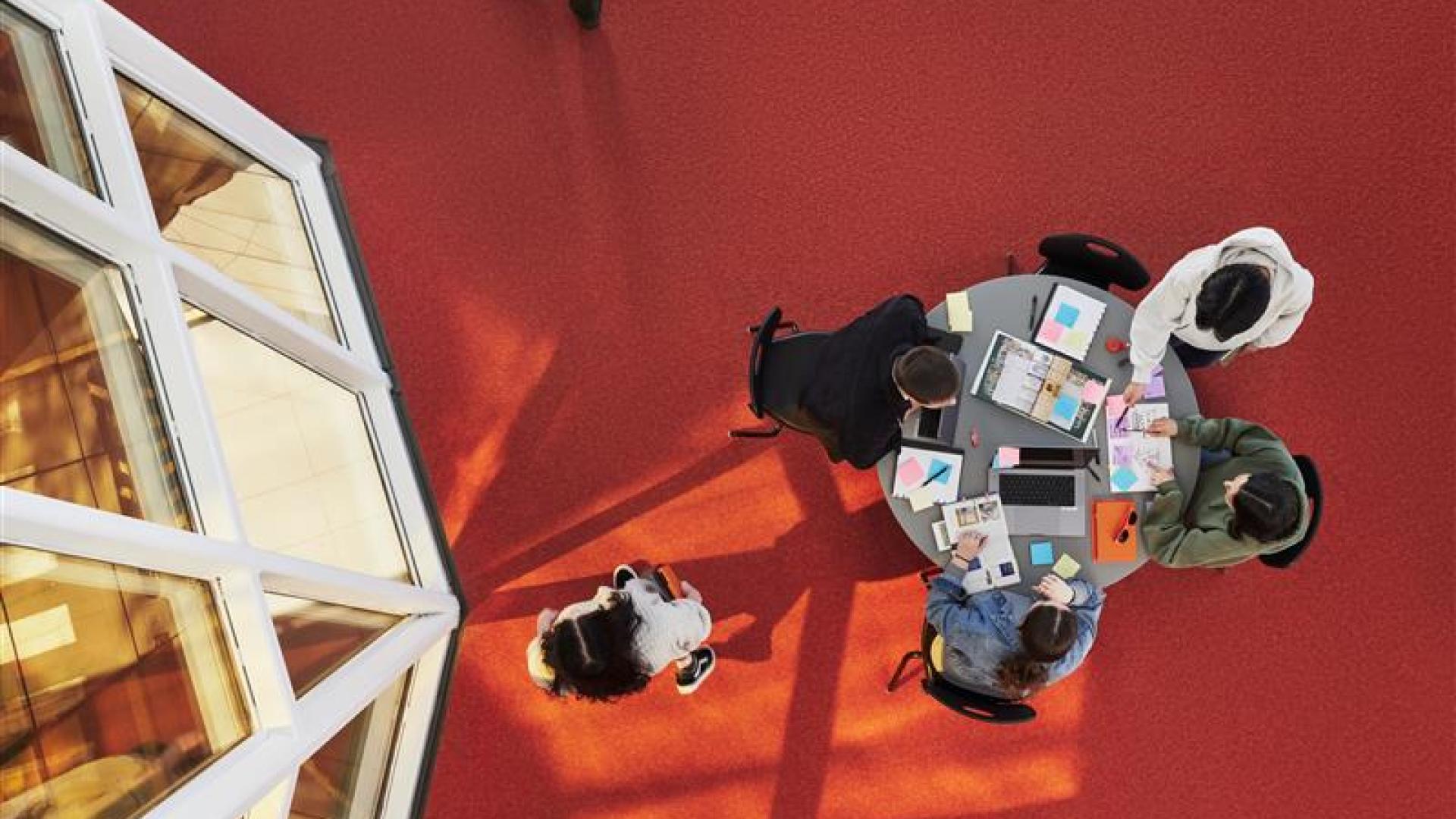 Photo shot from above: Four students studying at a table in T-building on Langara's Main Campus.