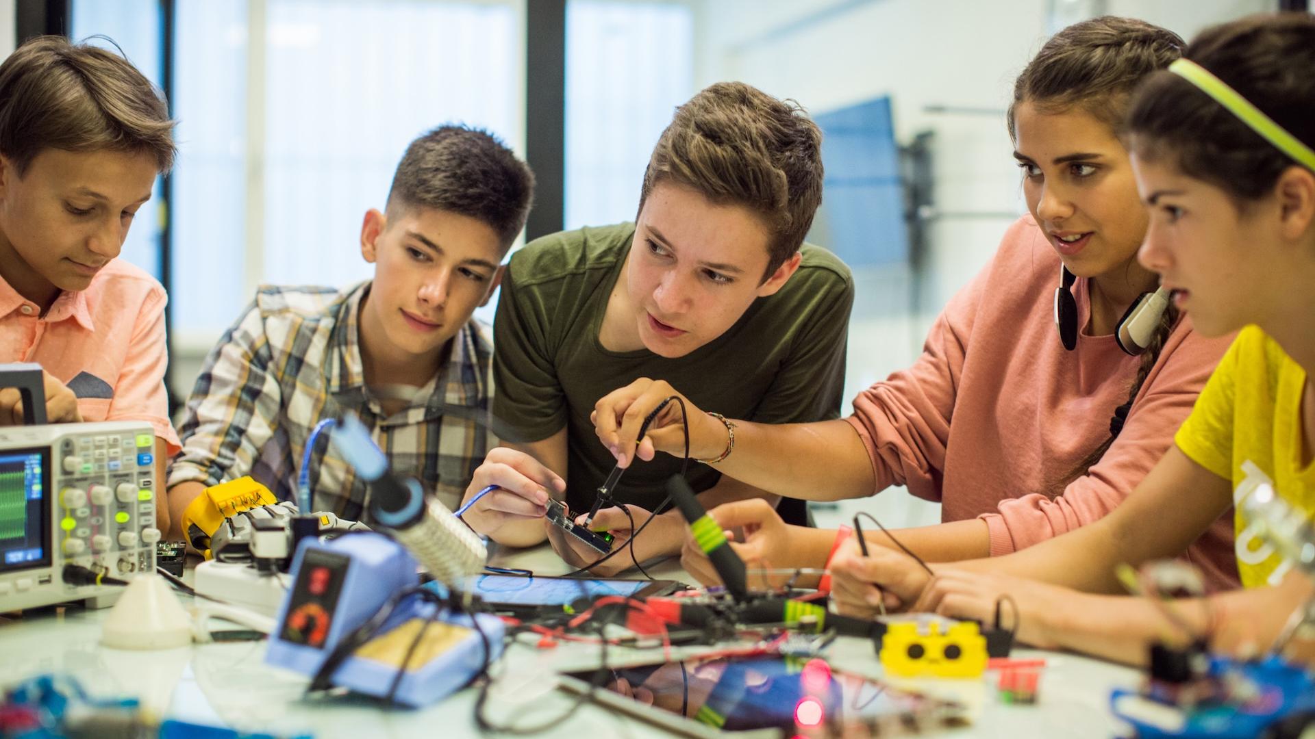 Five teens work on circuitboards to learn how they work during a summer camp session at Langara.