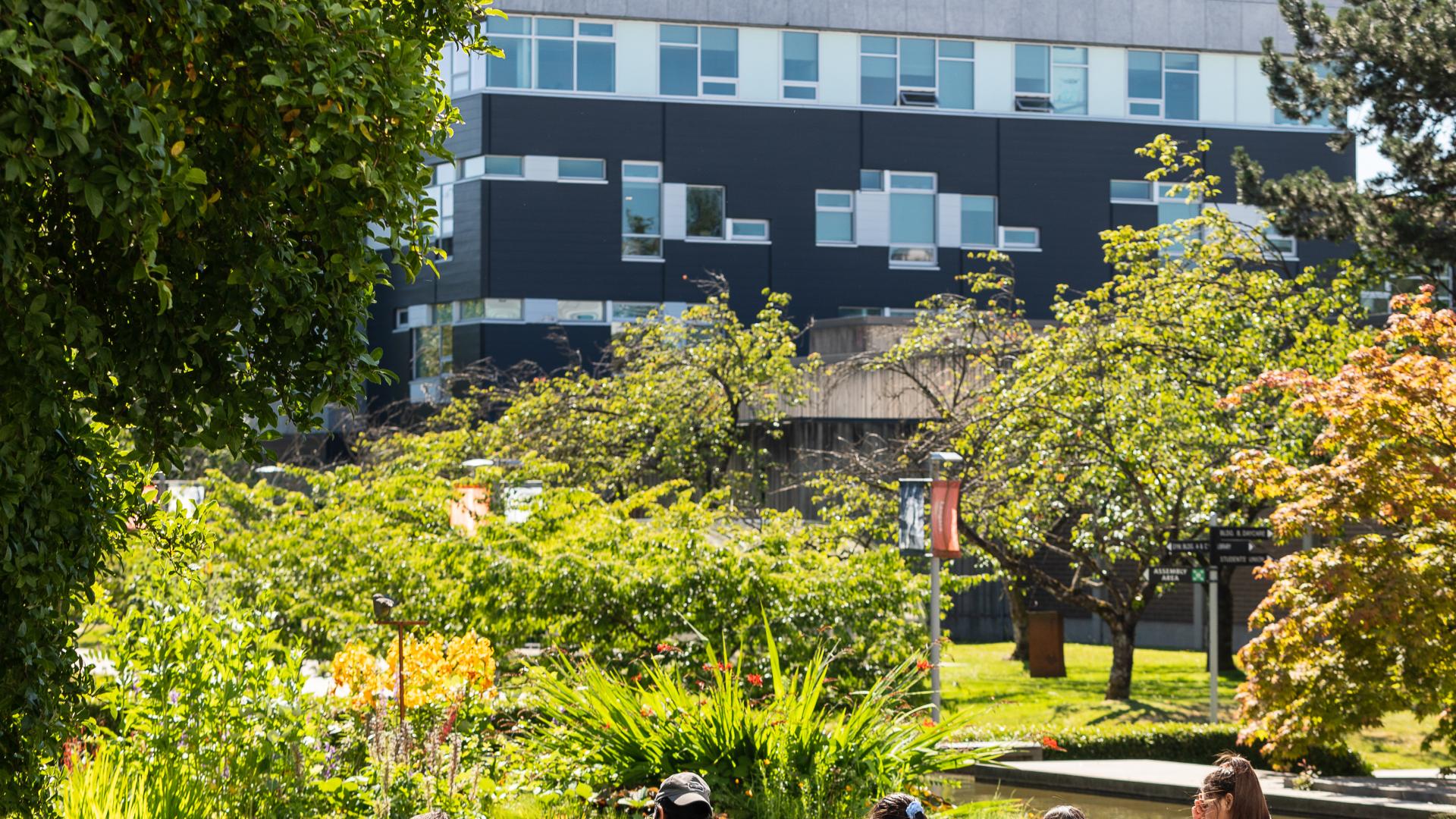 Five students sit on benches on campus.