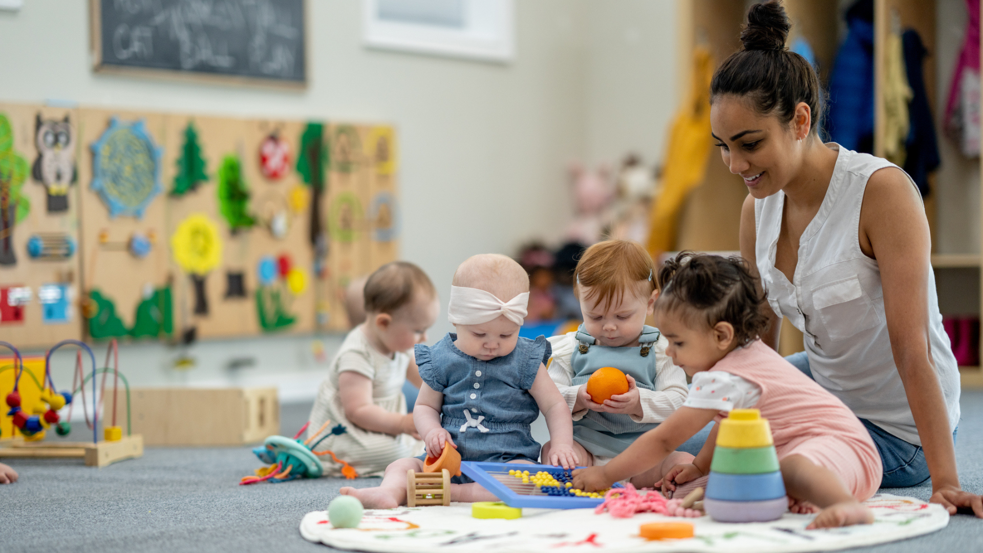 Teacher with toddler and infant students in an early childhood education centre.