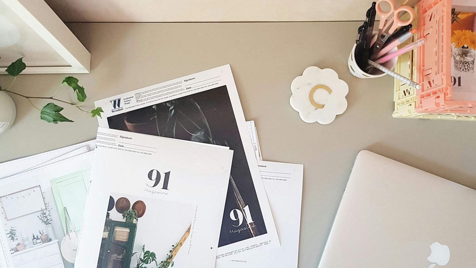 Magazine pages on a desk, a macbook laptop is also nearby.