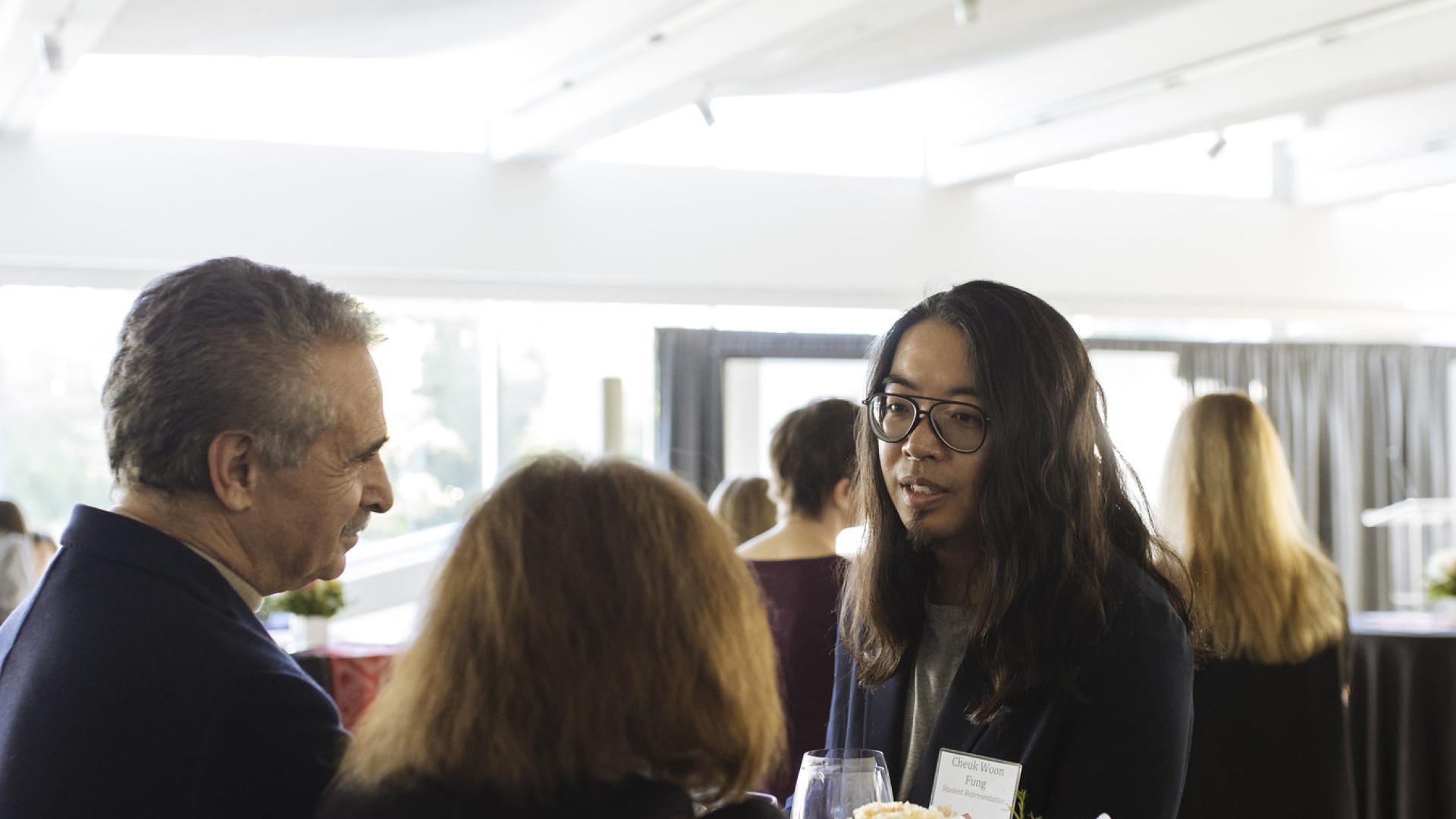 A student and two Langara donors standing and chatting at a table.