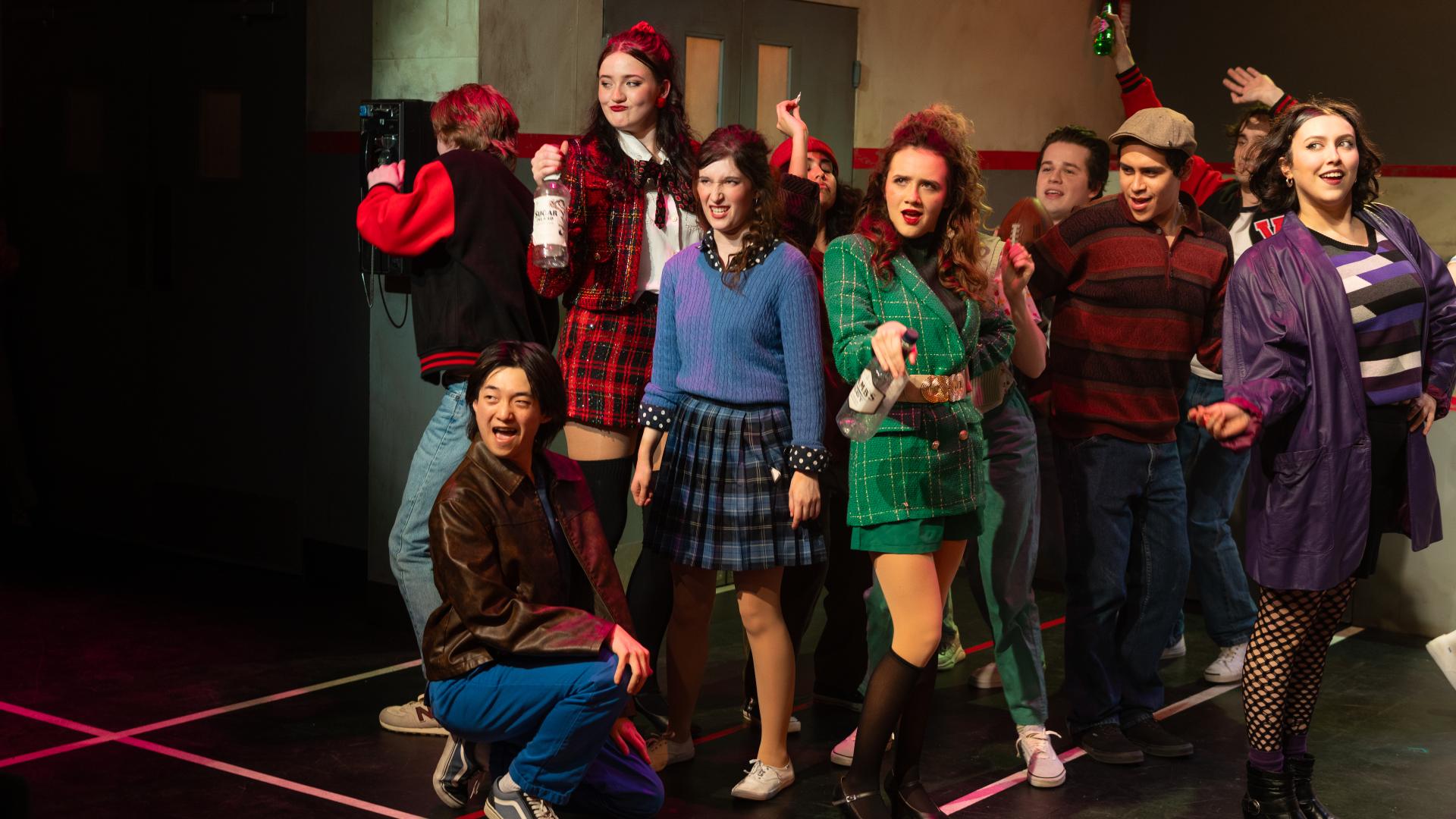 A group of high school students as the cast of Heathers are in a crowd all posing.