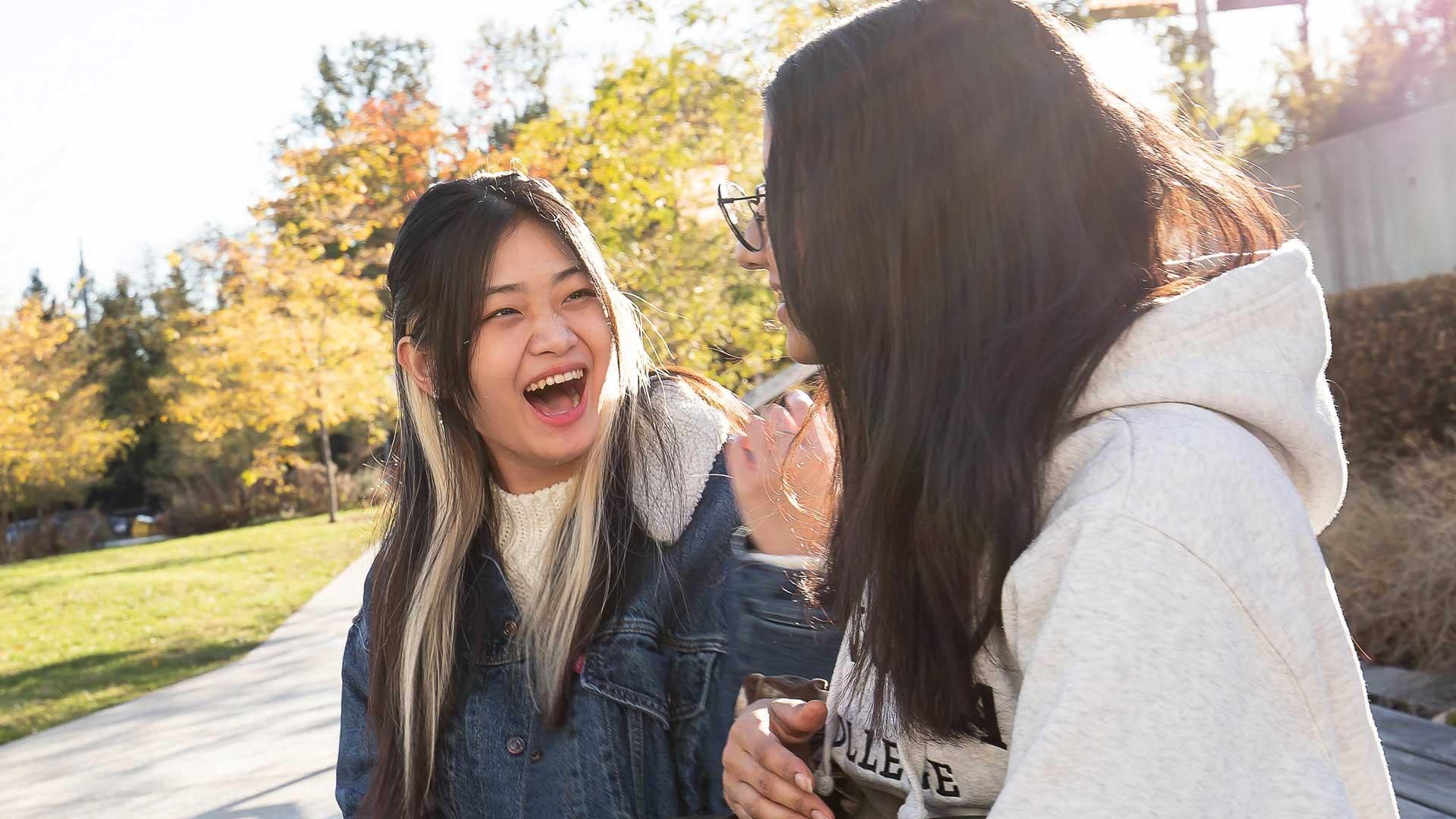 Two female-presenting students talk on Langara's main campus.