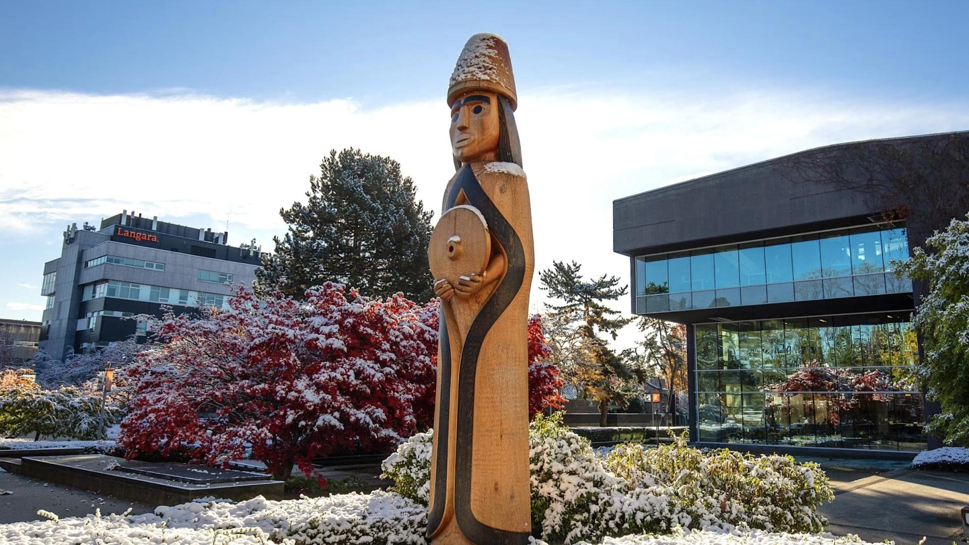 Musqueam welcome figure outside a snowy Langara College campus
