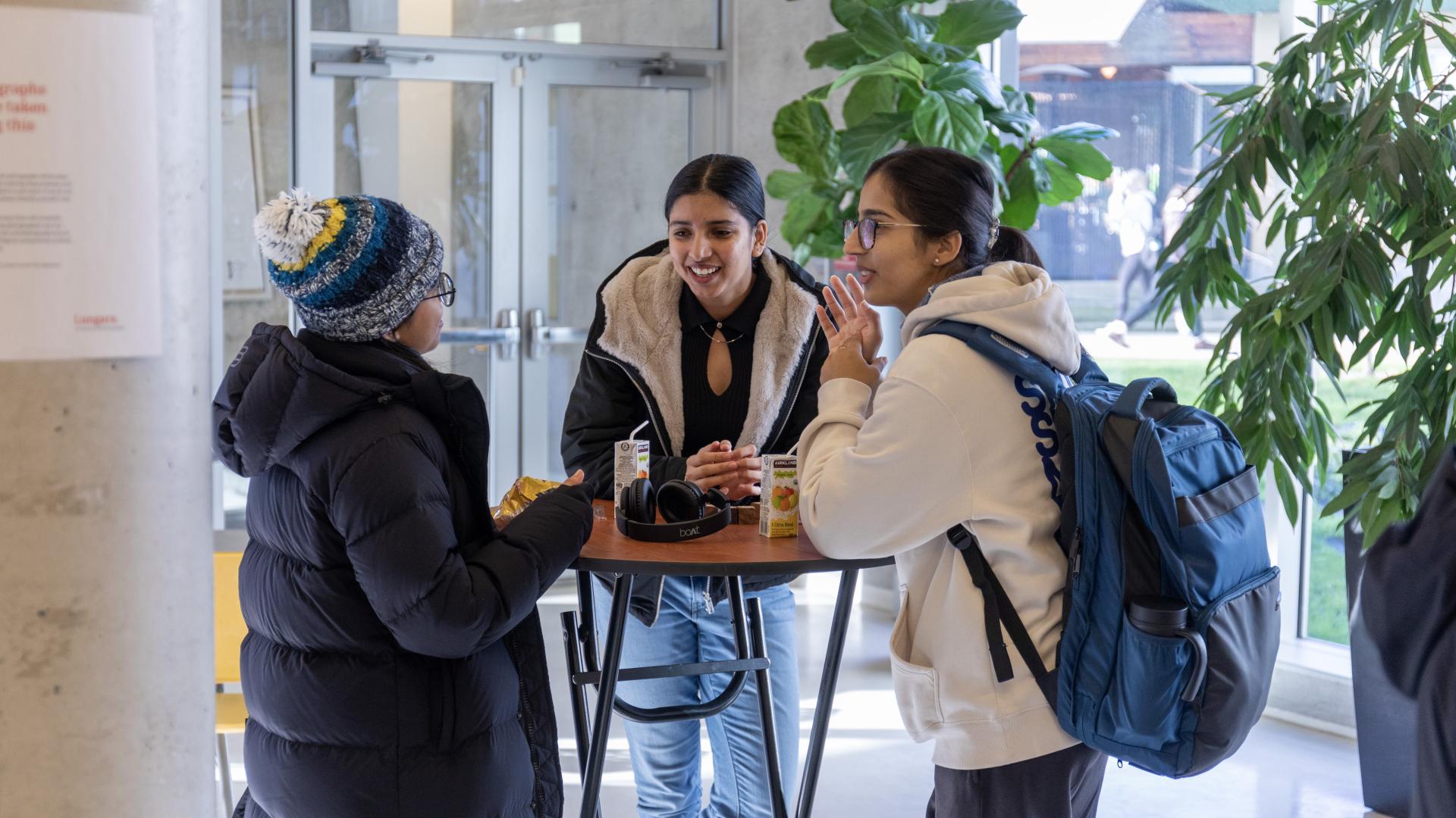 Three students gather around a table at the Student Union Buildling.