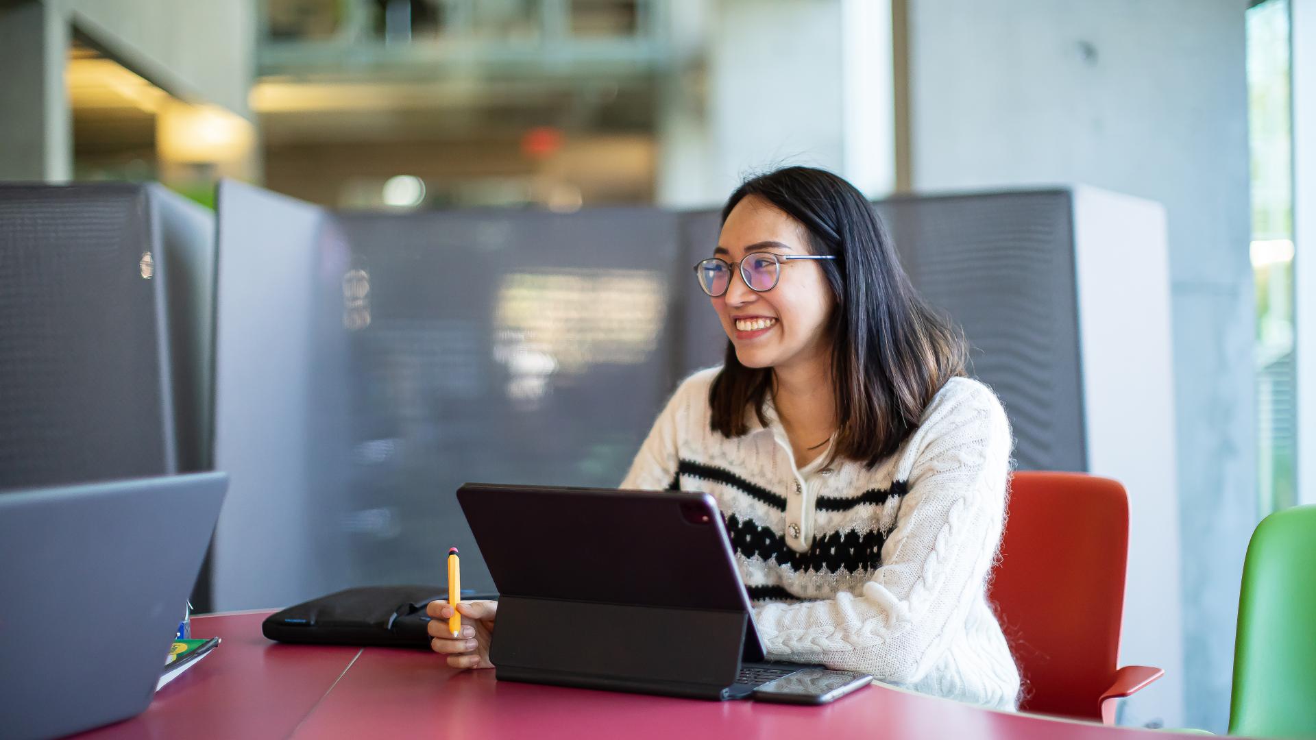 Female student sitting at a table in front of laptop computer.