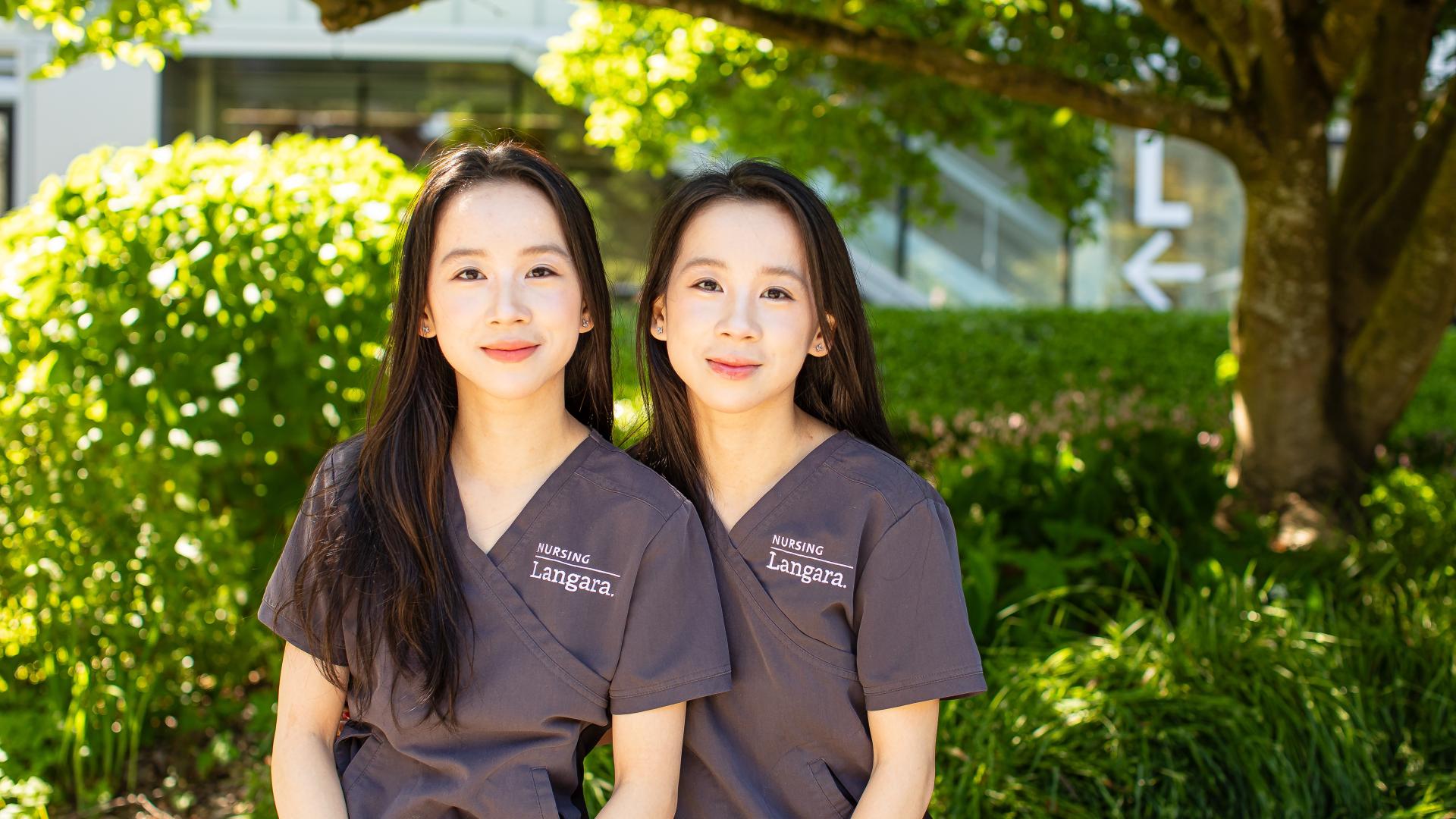 Nursing alum and sisters, Cecilia and Mandy He, sitting on a bench outside Langara's Science and Technology Building.