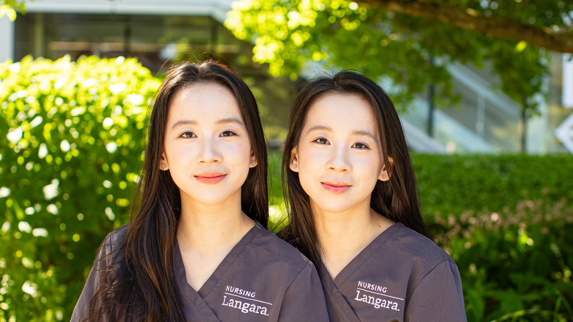 Nursing alum and sisters, Cecilia and Mandy He, sitting on a bench outside Langara's Science and Technology Building.