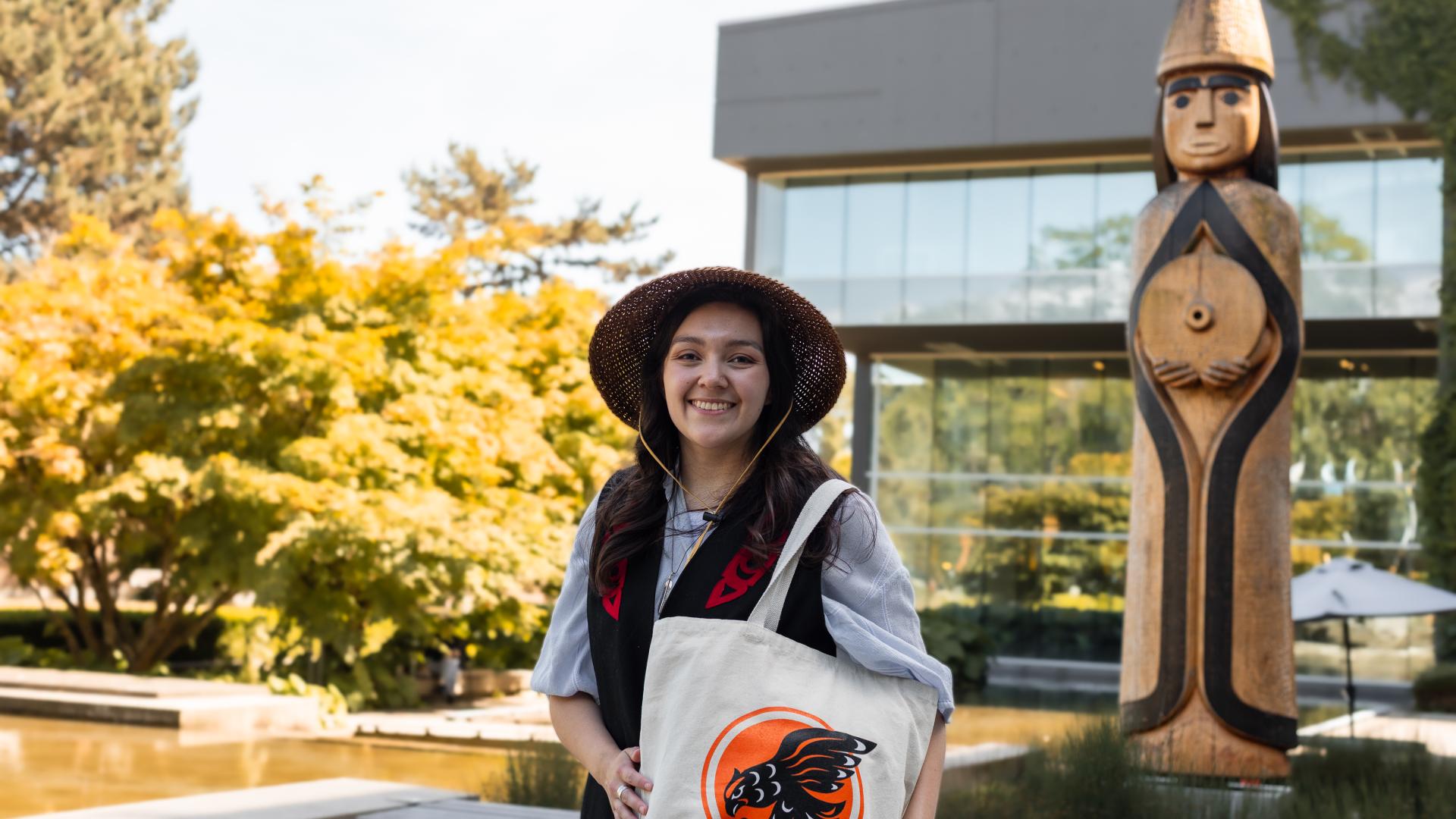 Musqueam alum, Amber Cornick, with her design of a Coast Salish-inspired Indigenous Langara Falcons logo, printed on a tote bag.