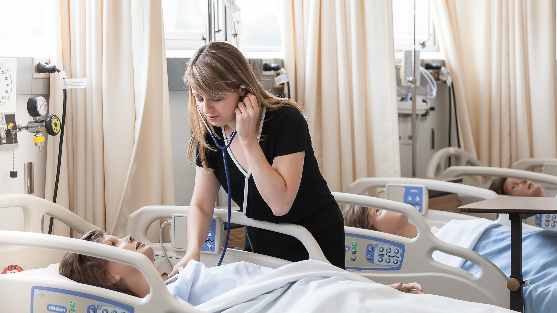 Student nurse caring for a mannequin patient in the nursing lab.