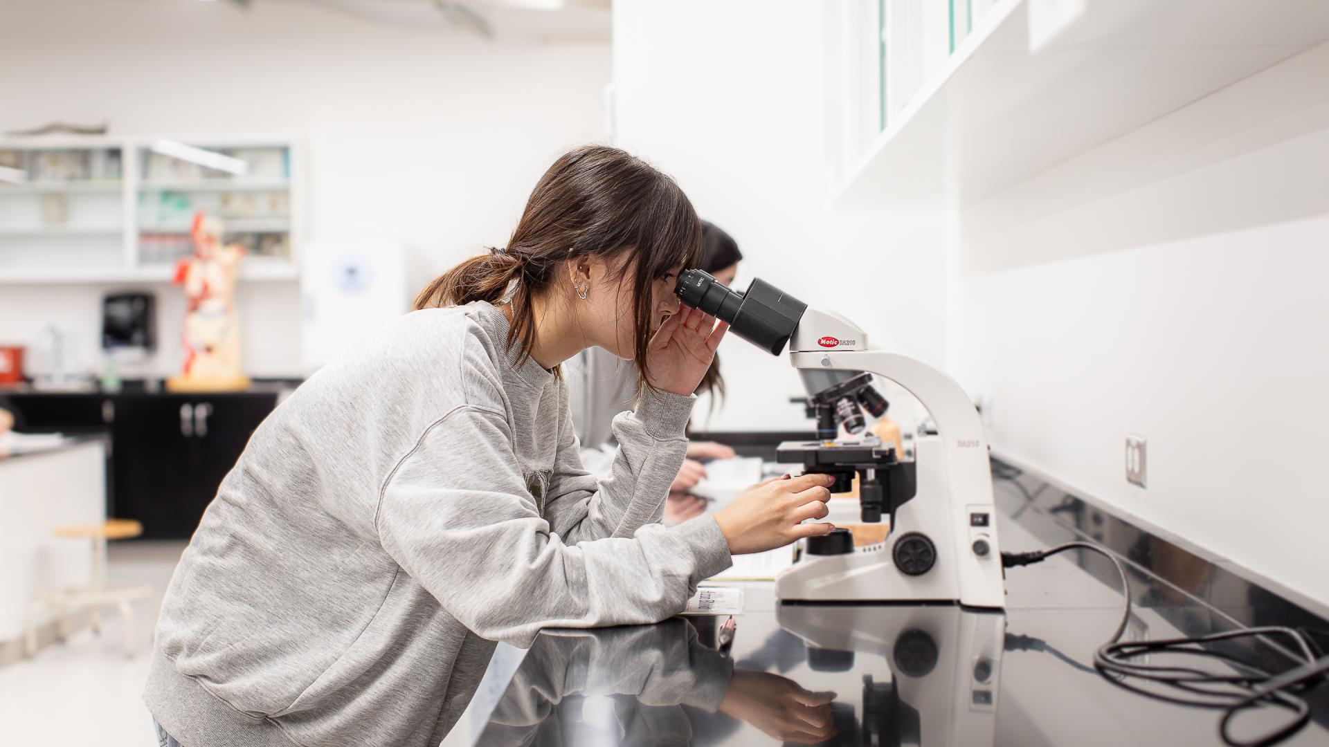 Biology student looking into a microscope in the biology laboratory.