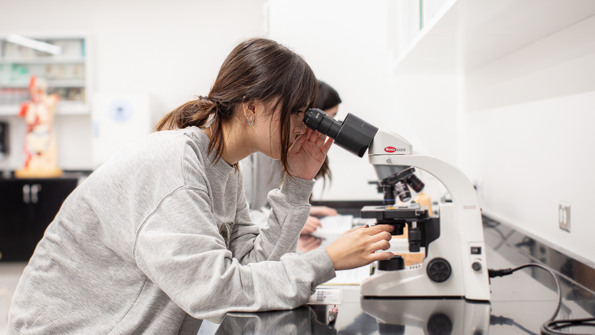 Asian Biology student looking into a microscope in the biology laboratory.