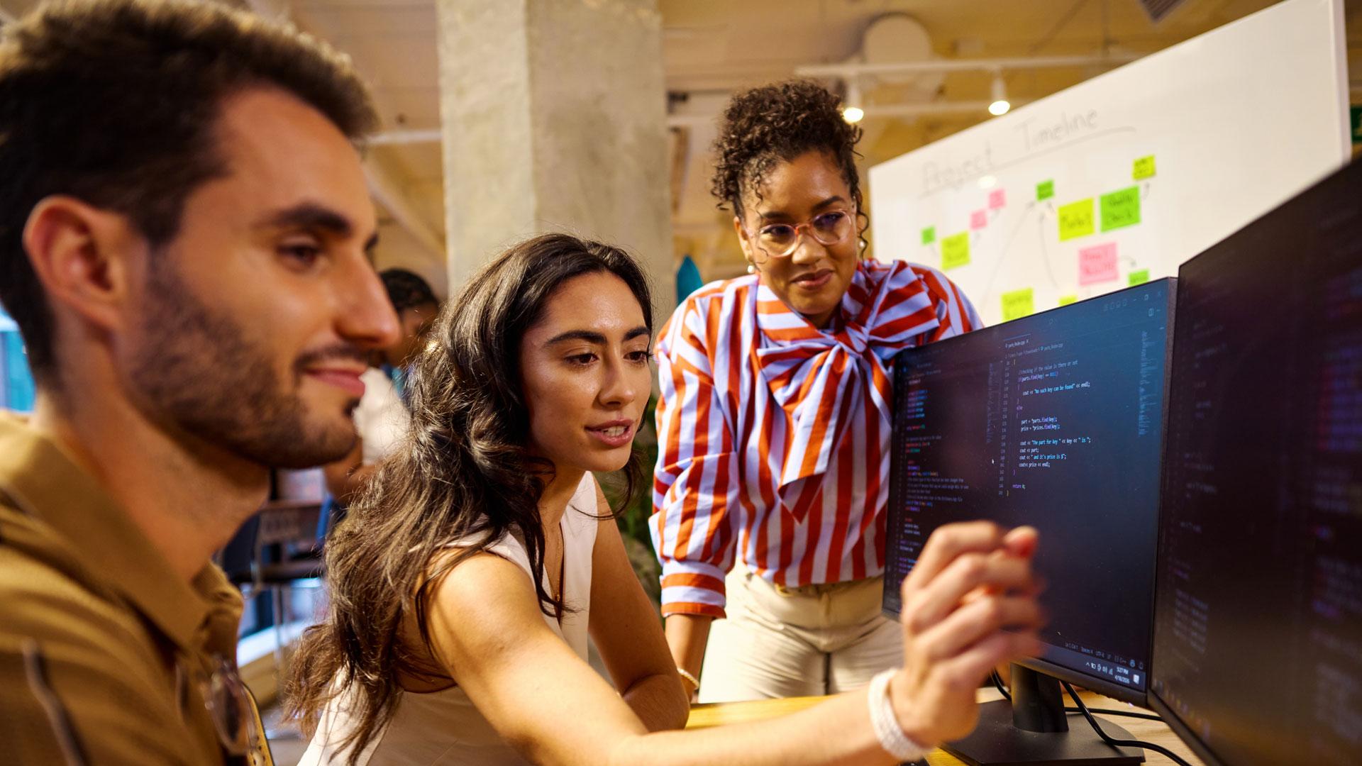 Three college students collaborating at a computer work station.