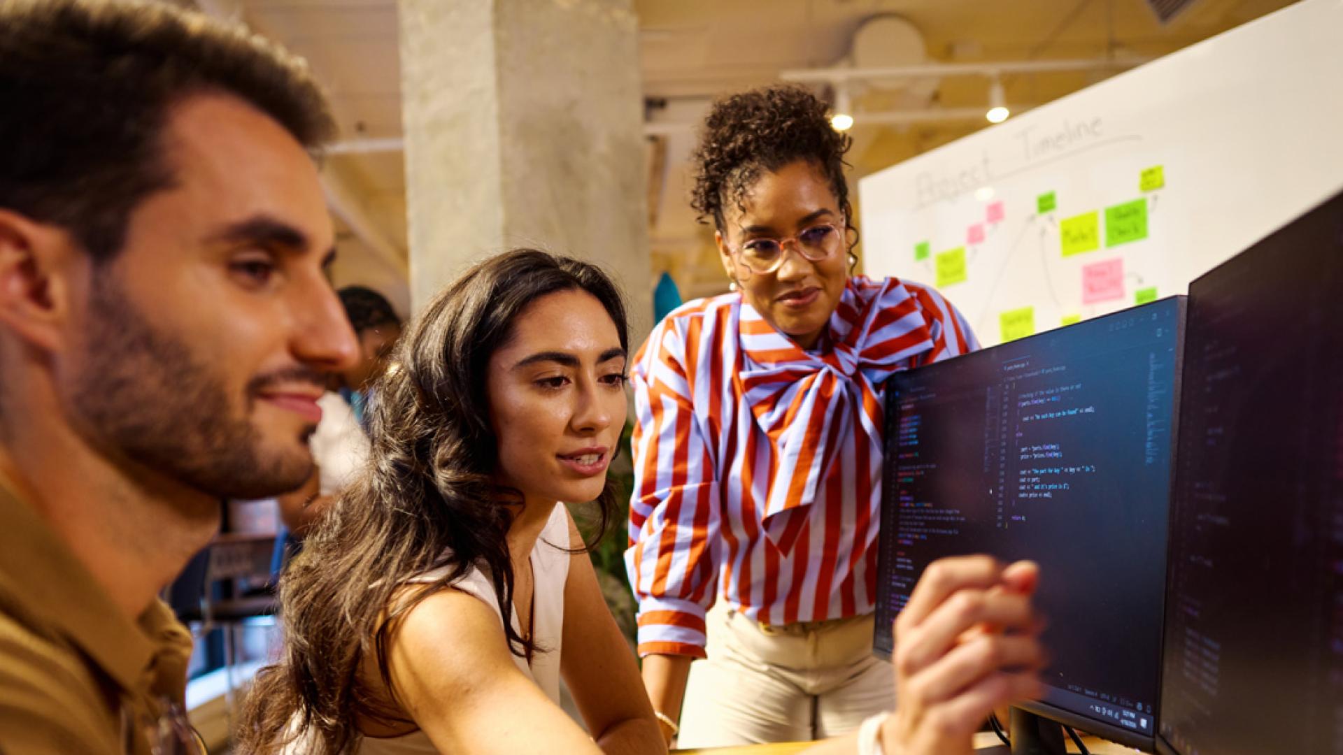 Three college students collaborating at a computer work station.