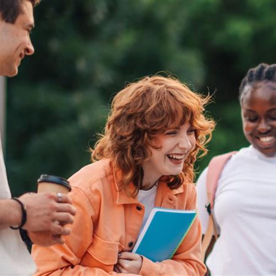 Three college students smiling while outdoors.