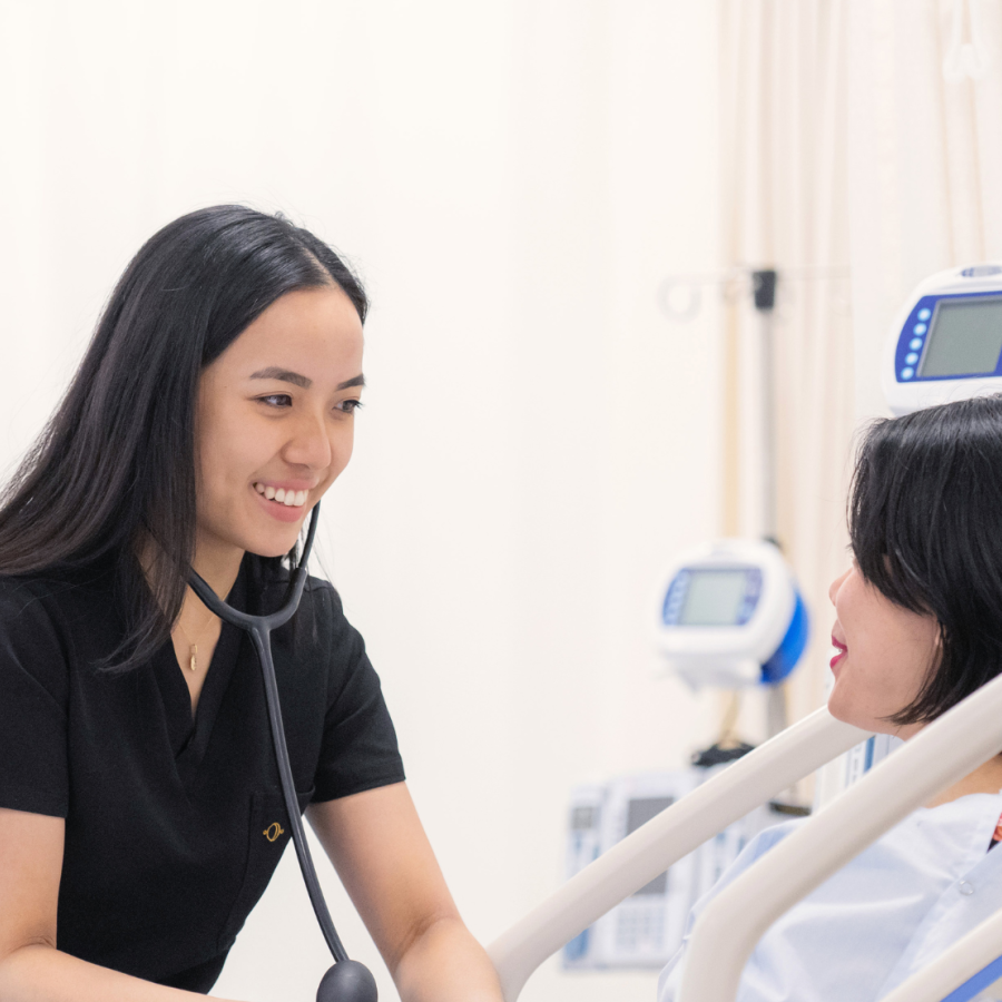 A nurse with a stethoscope providing care to a patient in a hospital bed.
