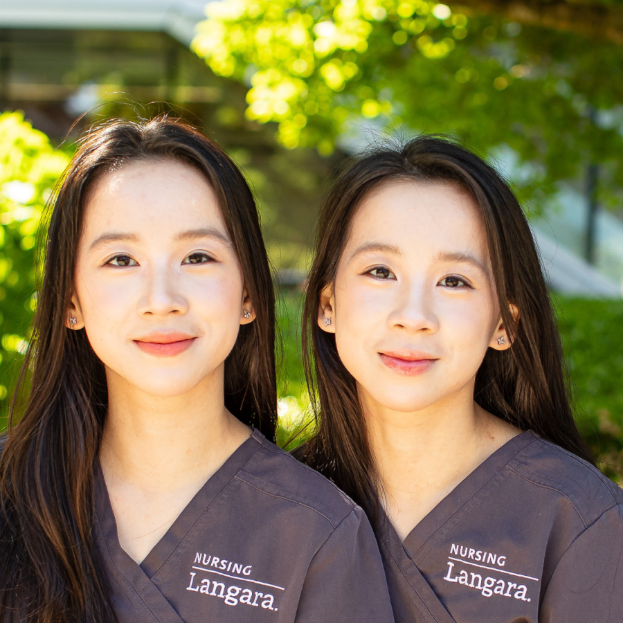 Nursing alum and sisters, Cecilia and Mandy He, sitting on a bench outside Langara's Science and Technology Building.