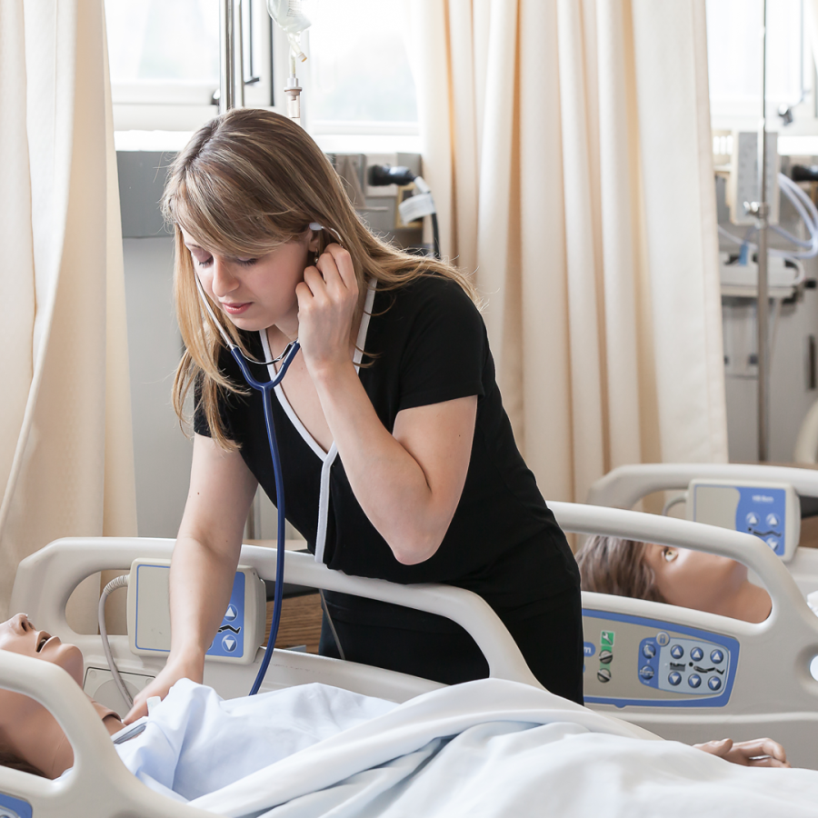 Student nurse caring for a mannequin patient in the nursing lab.
