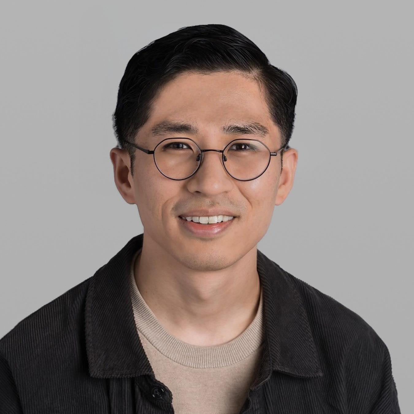 Headshot of David Alba, smiling, with round glasses and a dark jacket.