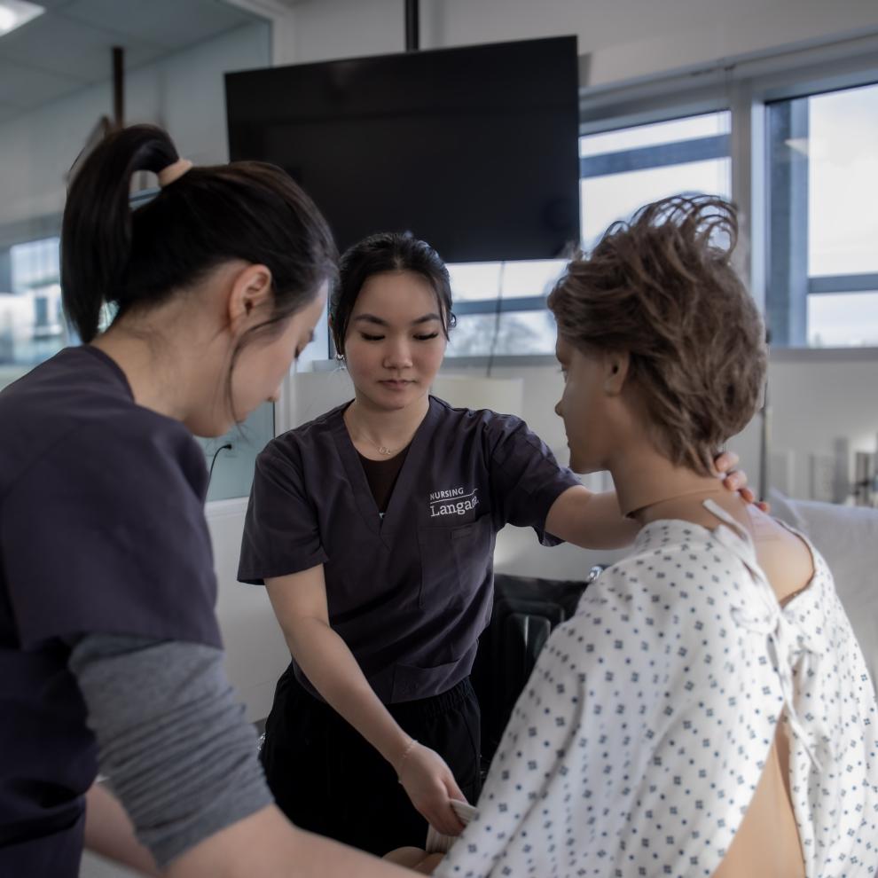 Theresa Mah arranges works with a patient simulation doll in Langara's nursing laboratory.