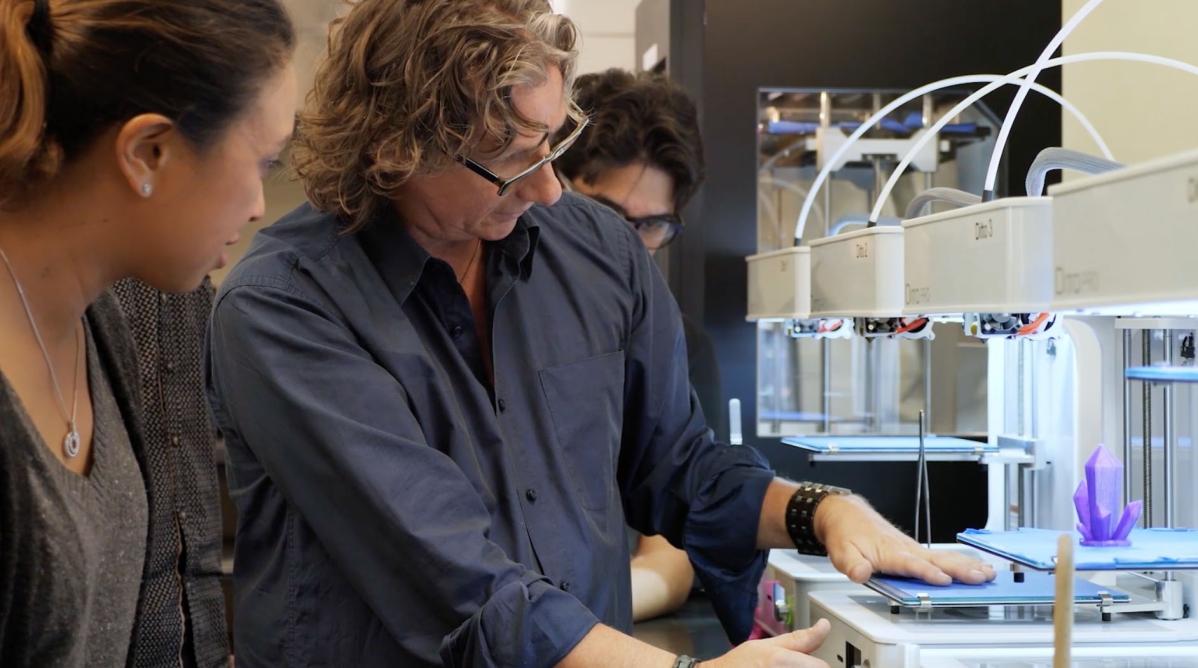 An instructor showing students how to use a 3D printer.
