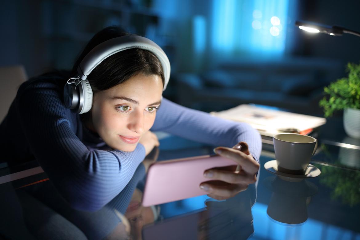 A woman intently watches her phone screen at night.