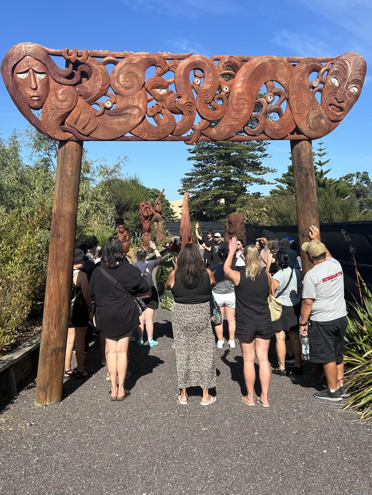 Langara delegation standing below a carved Māori gate.