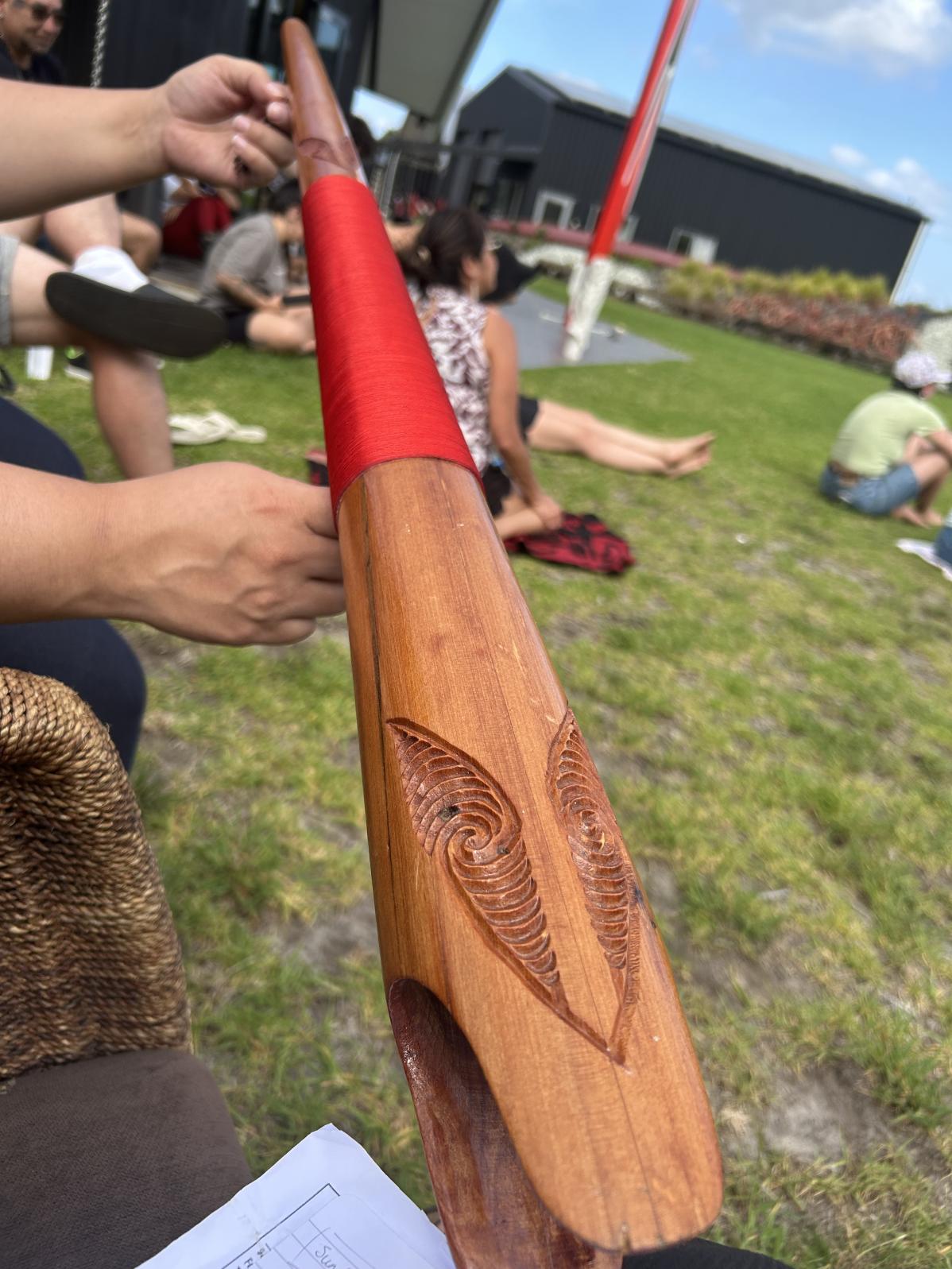 Hand holding a carved Māori item.