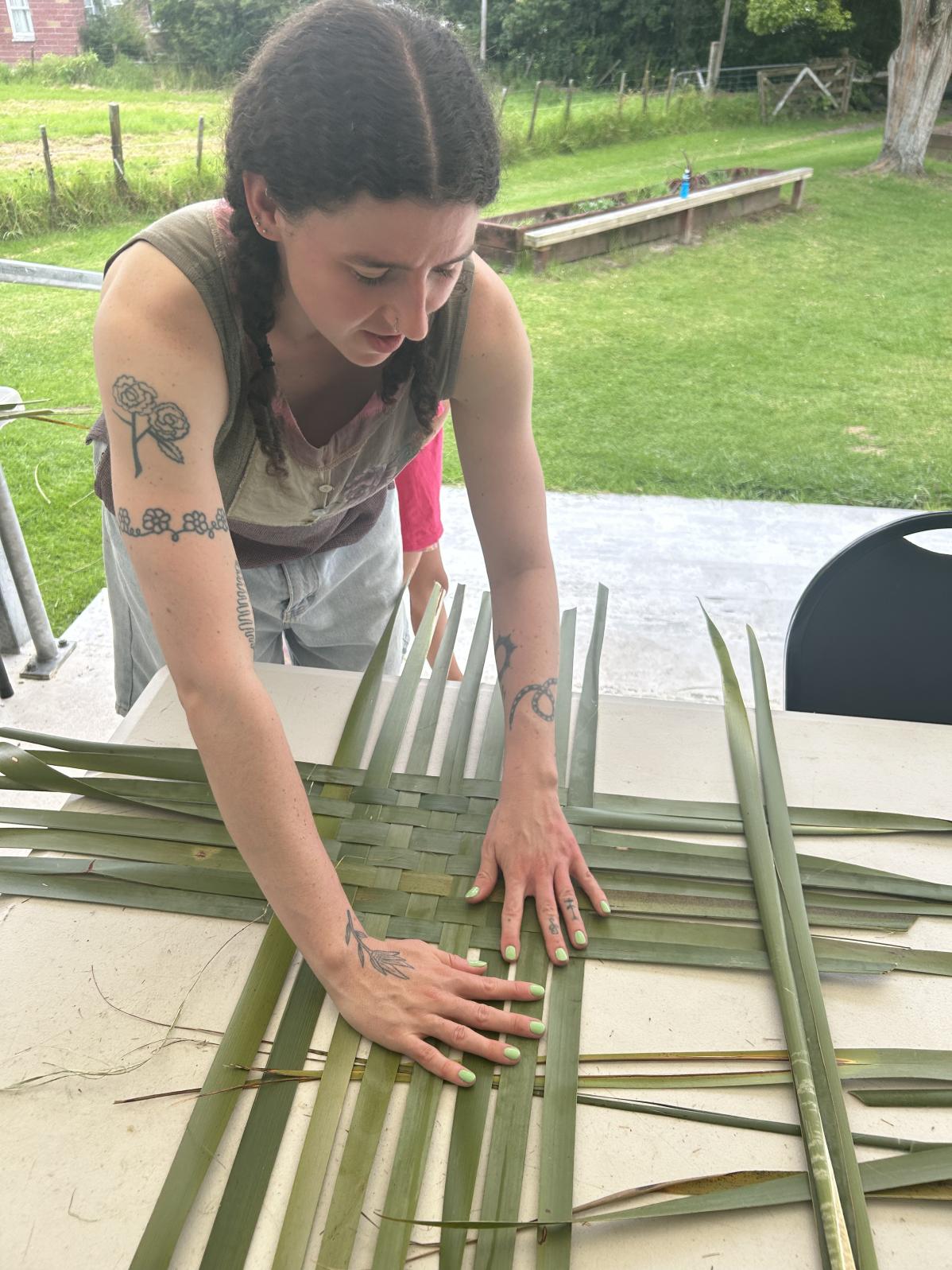 Young woman working on weaving leaves.