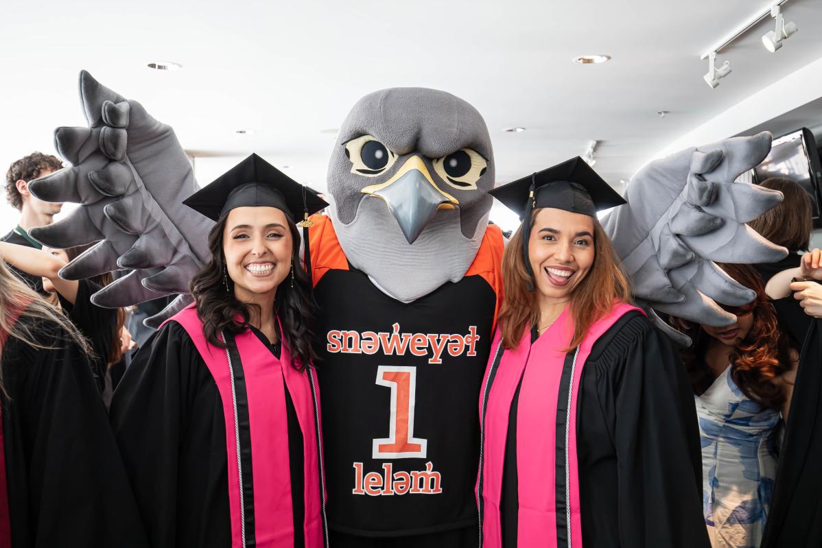 Two graduating students pose with Flash at convocation.