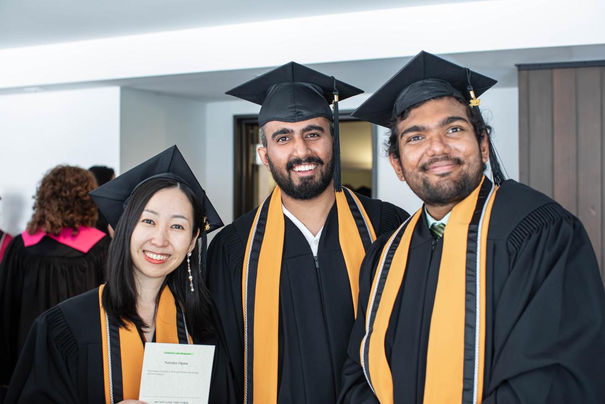 Three students pose wearing their caps and gowns.